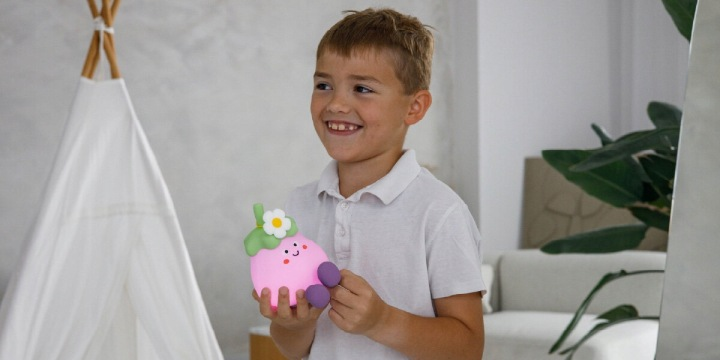Chłopiec trzyma różową zabawkę z kwiatową głową. W tle tipi.