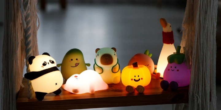 Urocze świecące lampki nocne w kształcie zwierząt i owoców na półce.