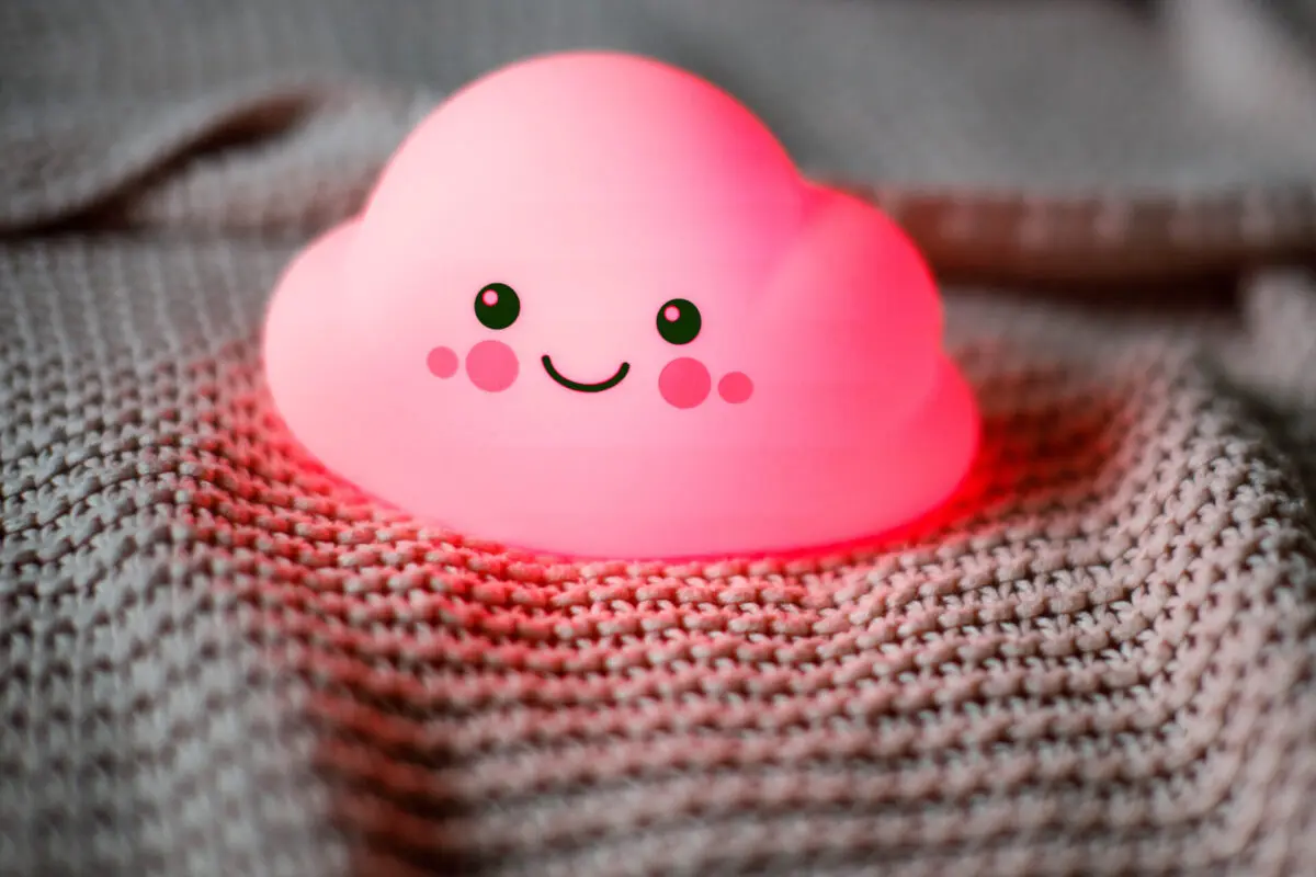 Świecąca różowa lampa chmurka z uśmiechniętą twarzą na dzianinie.
