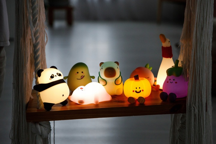 Urocze lampki w kształcie zwierząt i warzyw na półce.