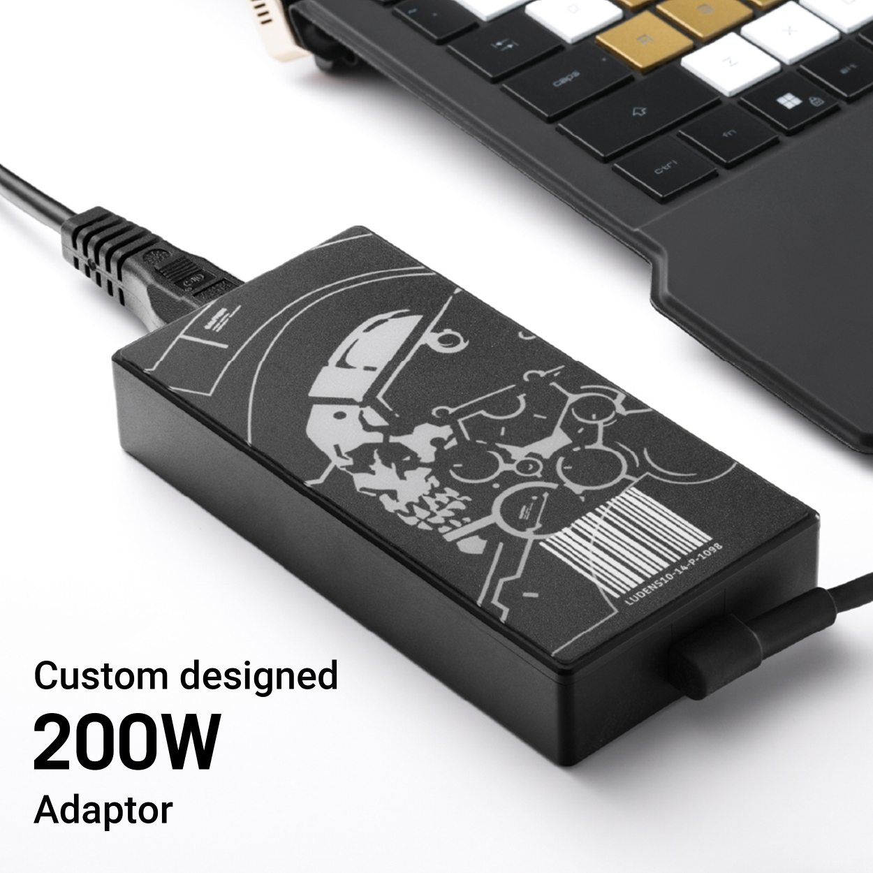 Schwarzer 200W Adapter mit Totenkopfdesign neben Laptop-Tastatur.