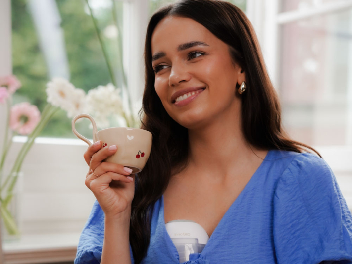 Kobieta z brązowymi włosami w niebieskiej bluzce trzyma kubek z wiśniami.