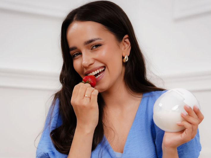 Kobieta je truskawkę i trzyma białą kulę.