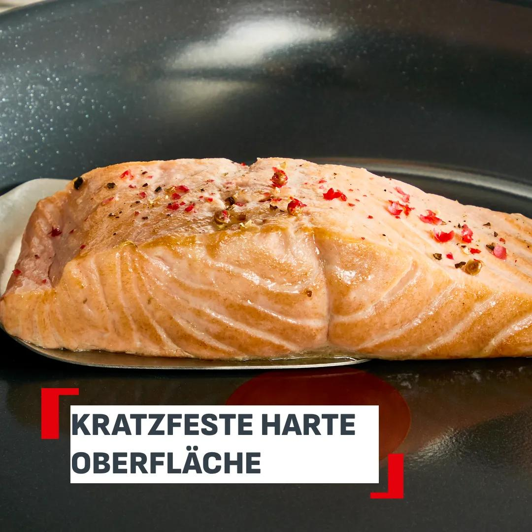 Gebratenes Lachsfilet mit rosa und schwarzen Pfefferkörnern in einer Pfanne.