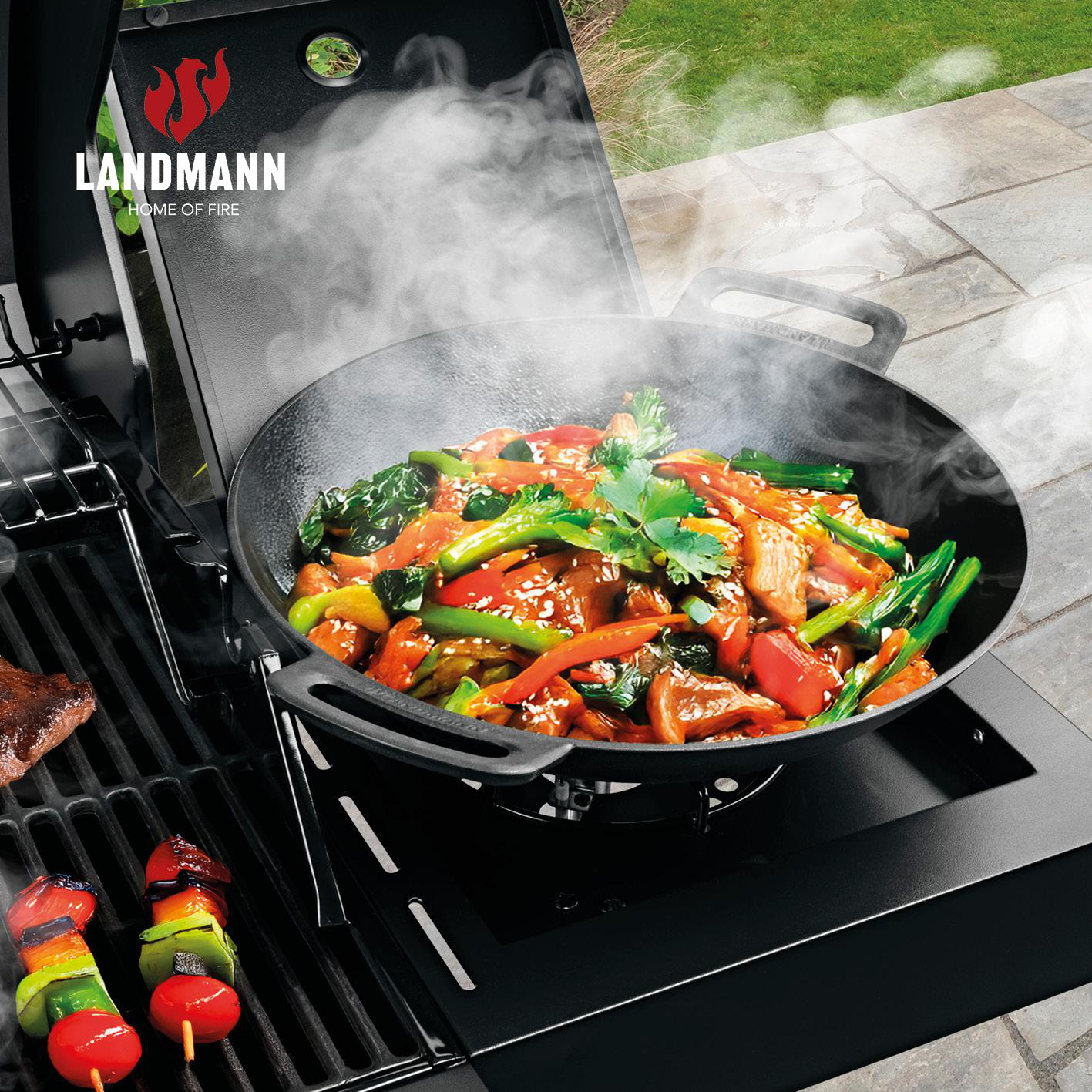 Fleisch und Gemüse werden in einem Wok auf einem Grill zubereitet.