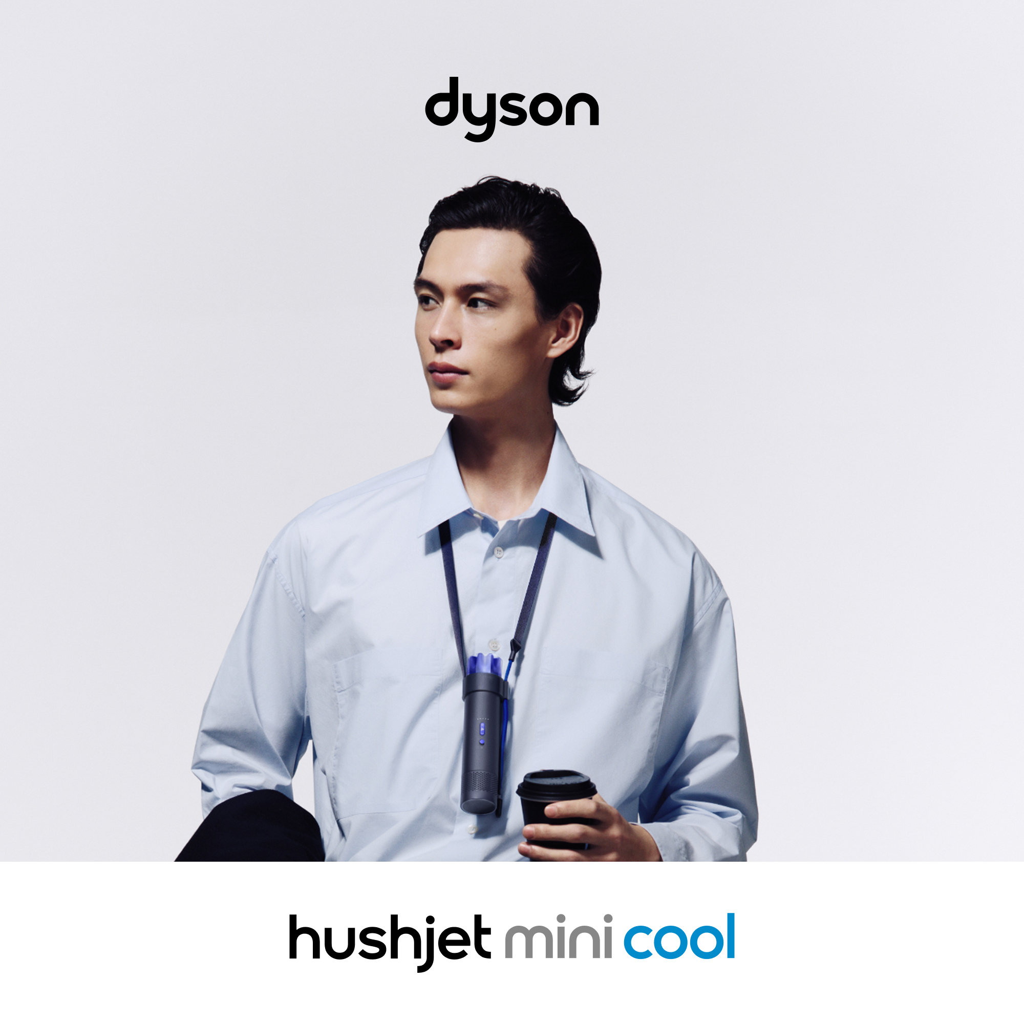 Mann mit Dyson-Gerät am Hals und Kaffeetasse in der Hand.