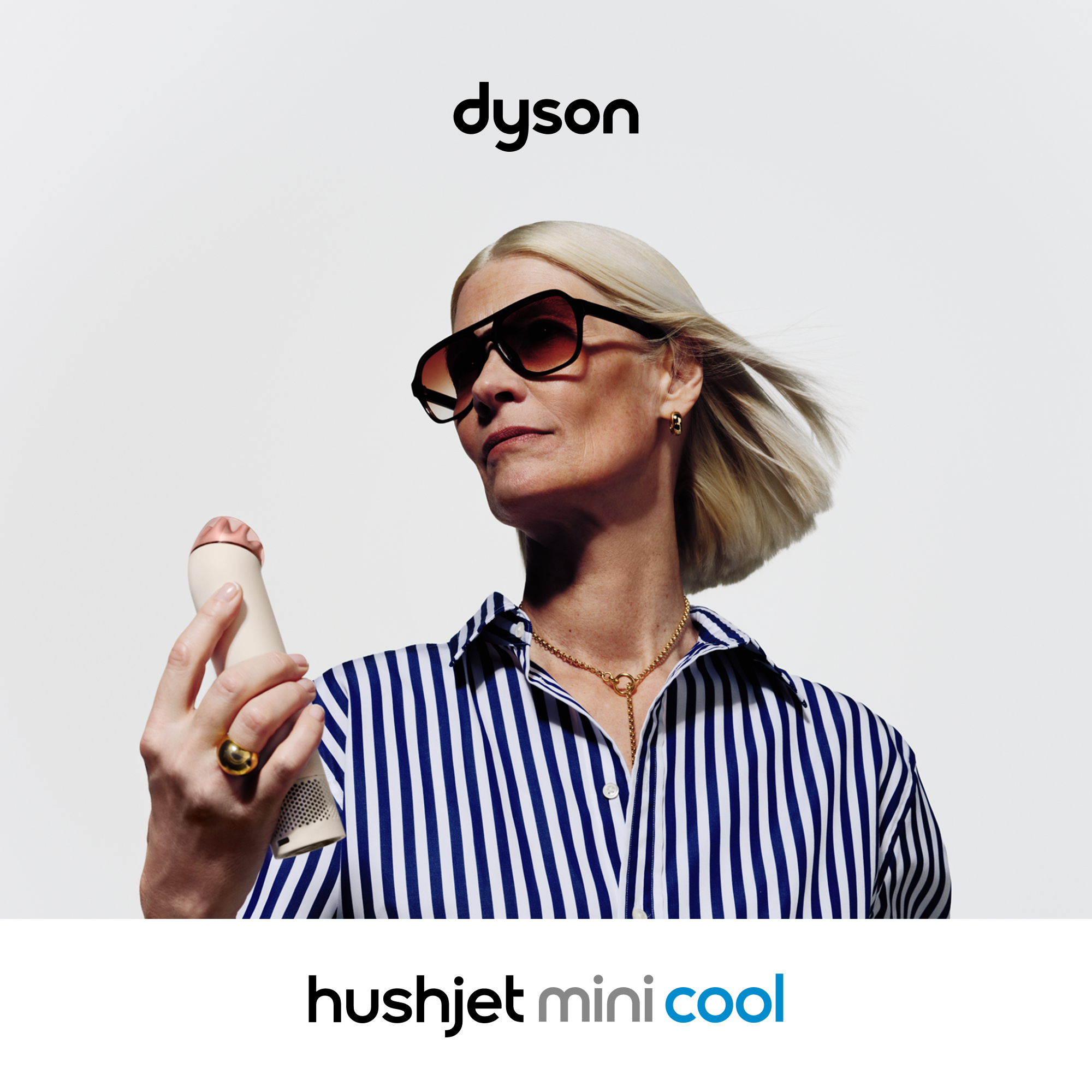 Frau mit Sonnenbrille und gestreiftem Hemd hält Dyson hushjet mini cool.