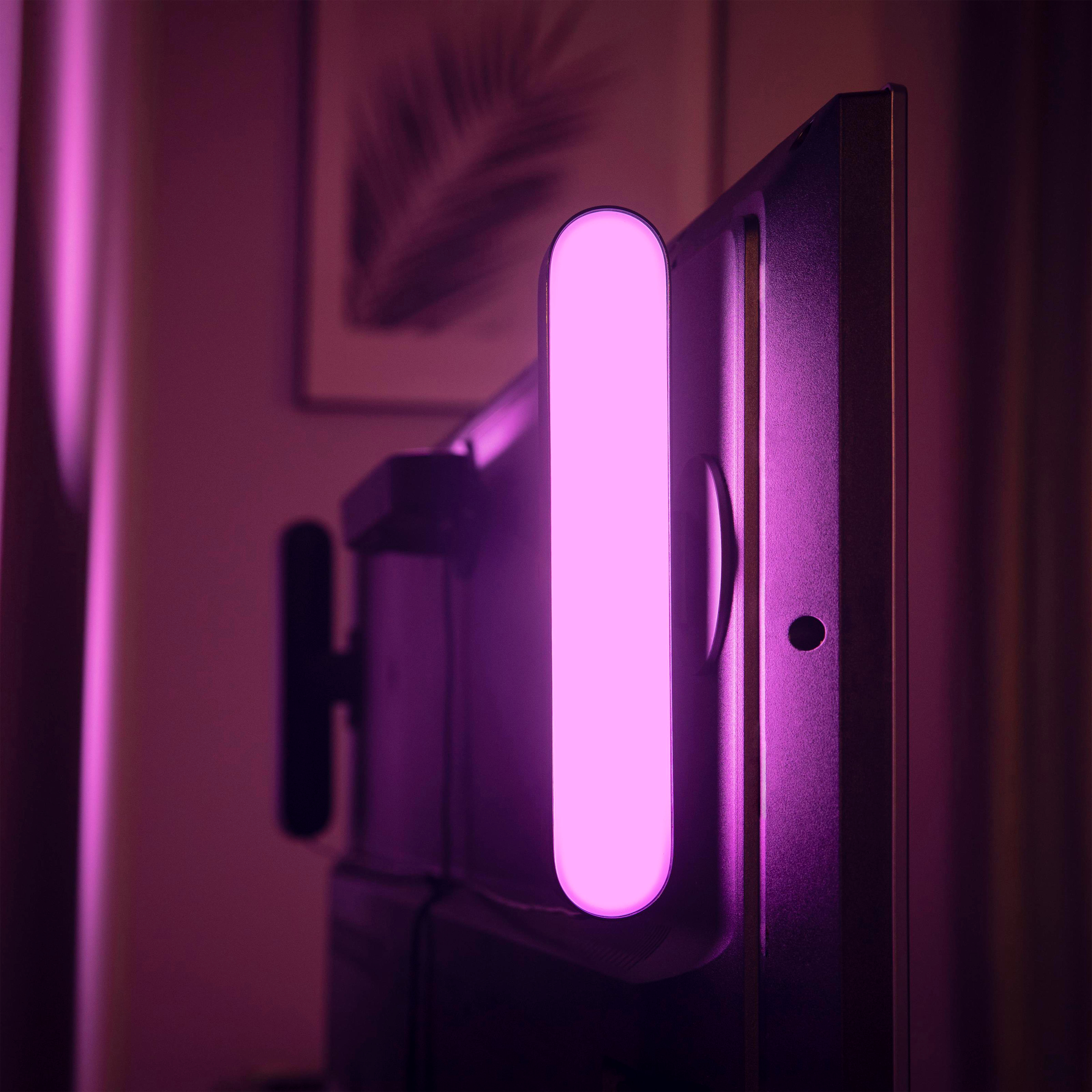 Eine pinke LED-Lichtleiste ist an der Rückseite eines Fernsehbildschirms in einem schwach beleuchteten Raum angebracht.