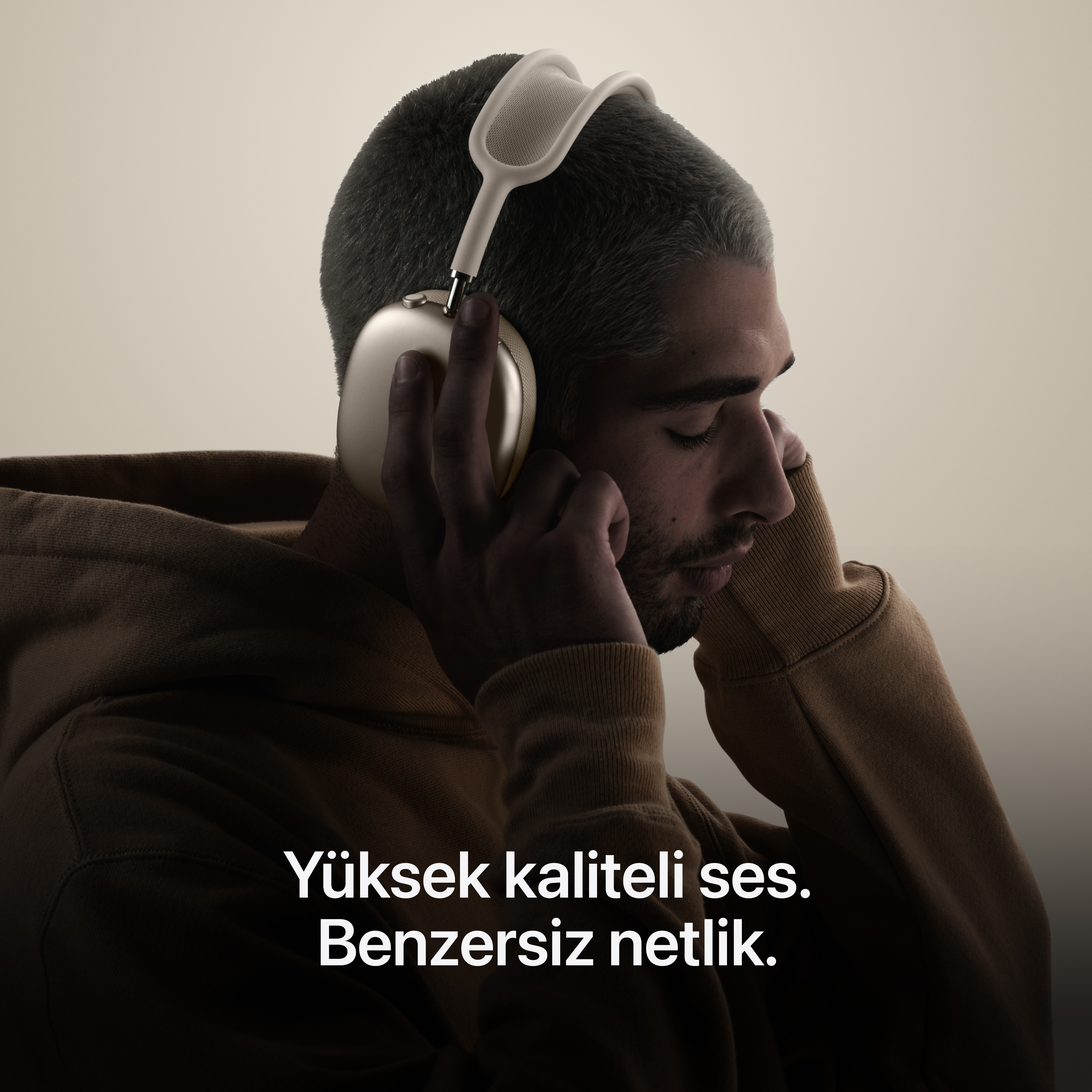 Altın rengi kulaklıklı adam müzik dinliyor, profilden.