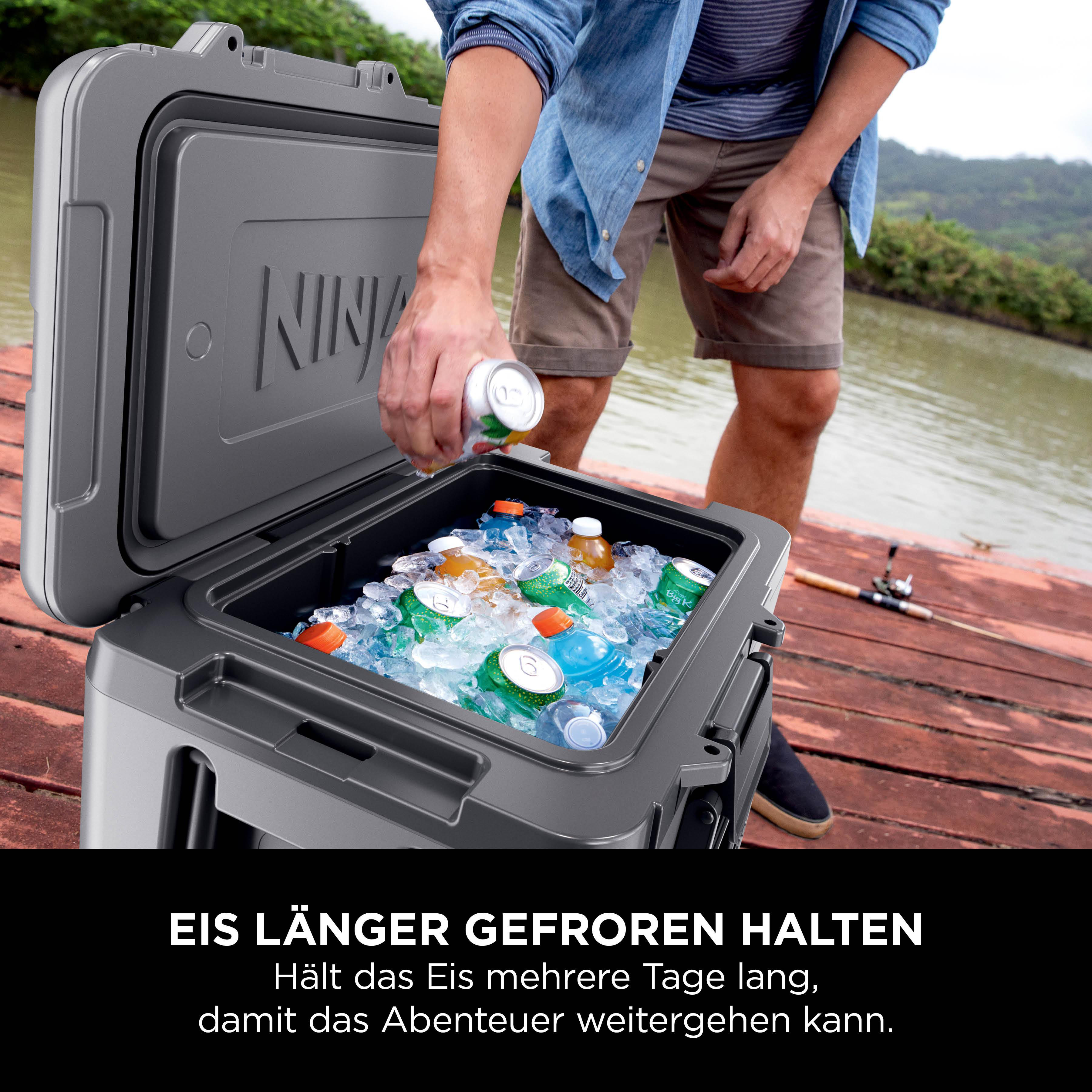 Mann füllt Dosen und Flaschen in einen grauen Kühlbox mit Eis am Seeufer.