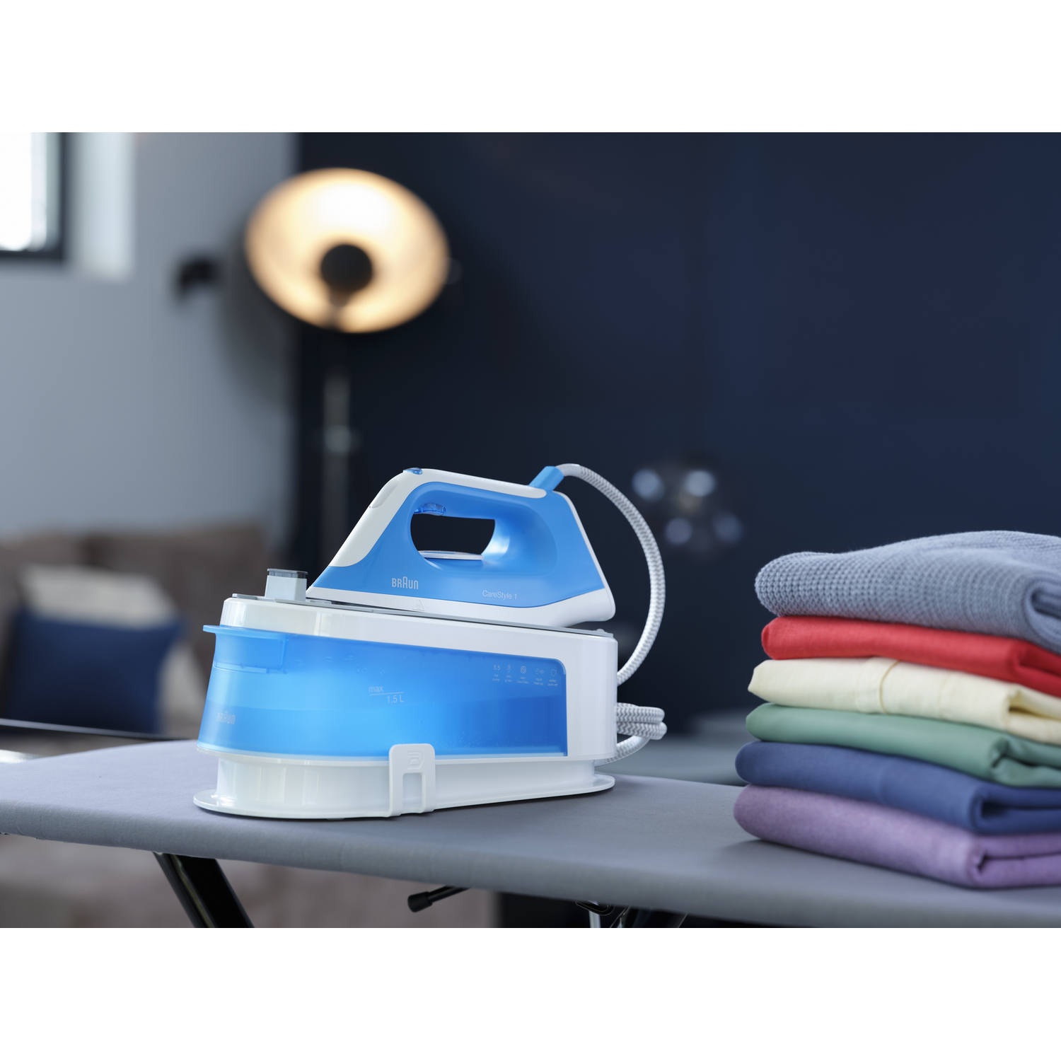 A blue steam iron station with an iron and folded clothes.