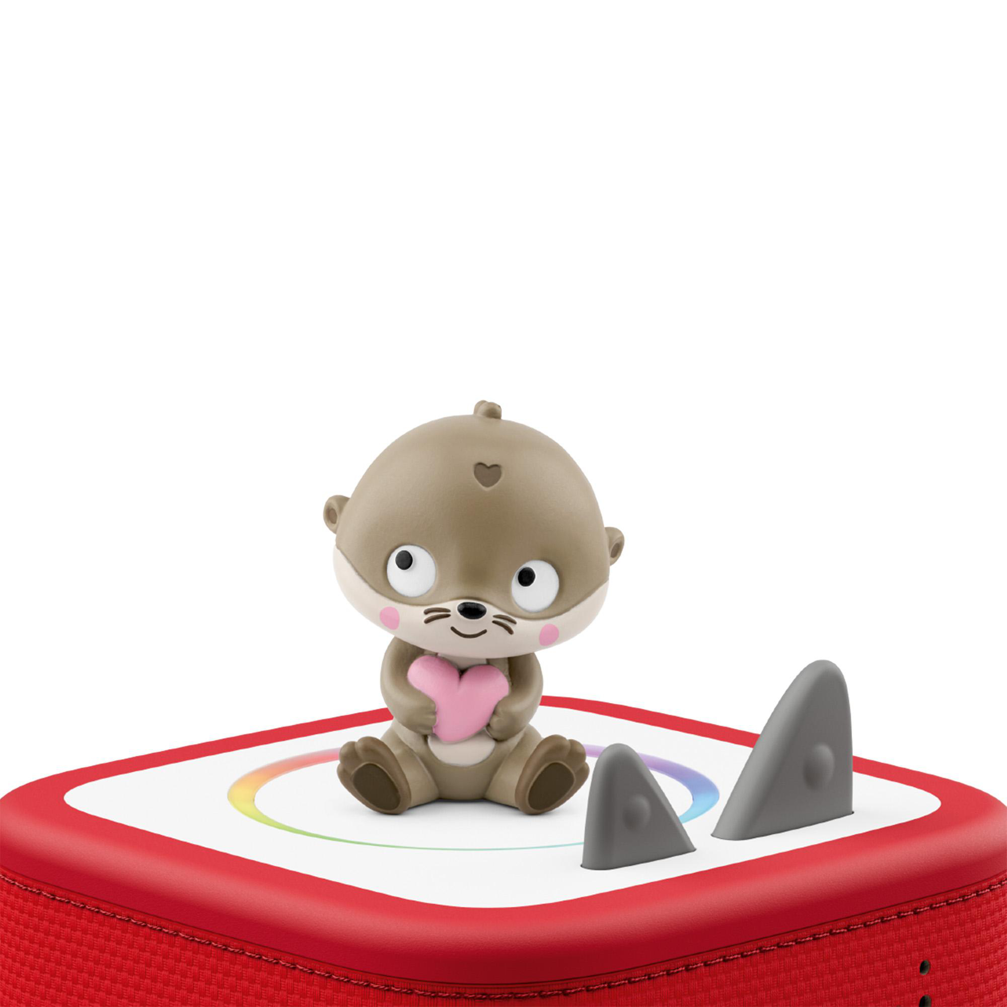 Ein Otter-Spielzeug hält ein Herz auf einem roten Gerät mit Regenbogenlicht.