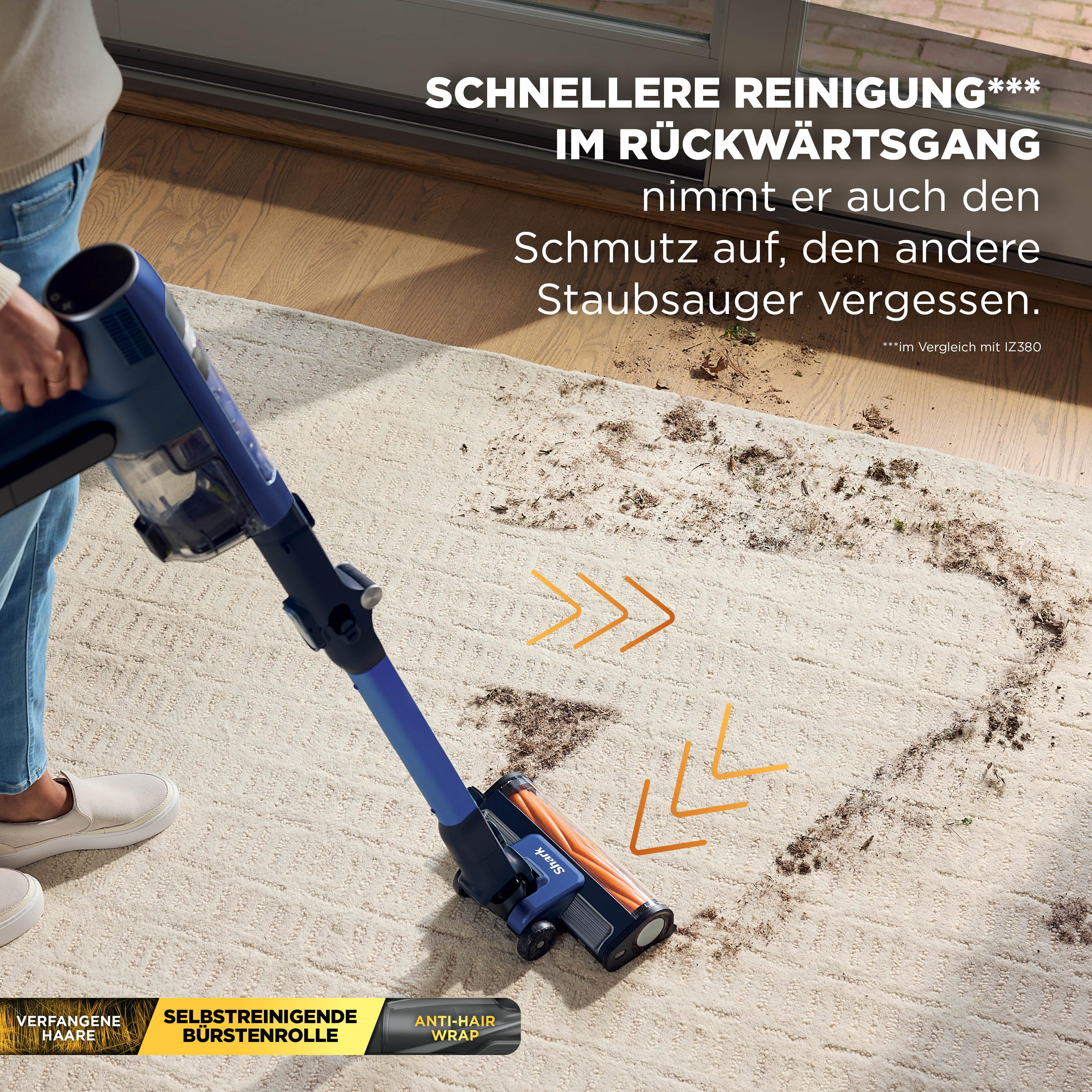Ein blauer Staubsauger reinigt einen Teppich mit Schmutz.