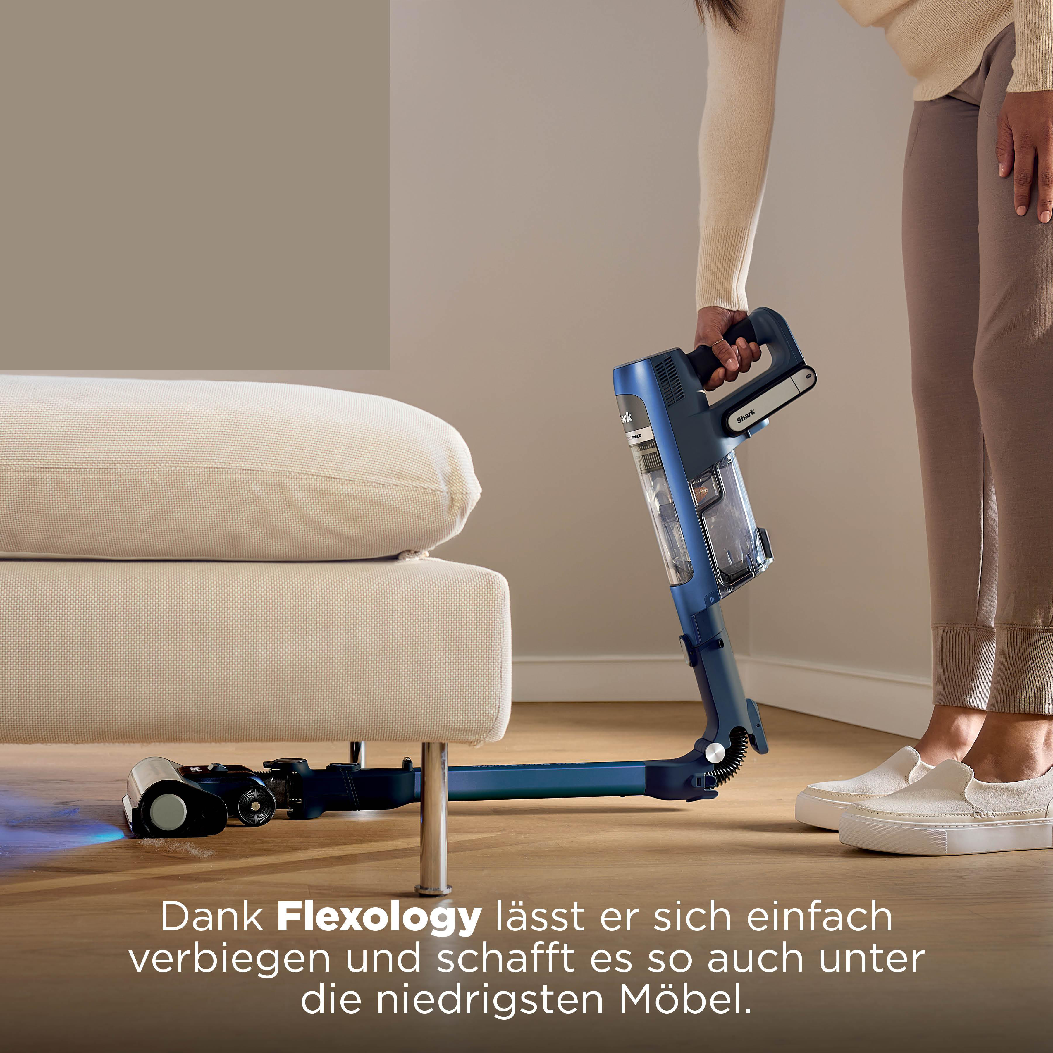Eine Person reinigt den Boden mit einem blauen Staubsauger unter einem Sofa.