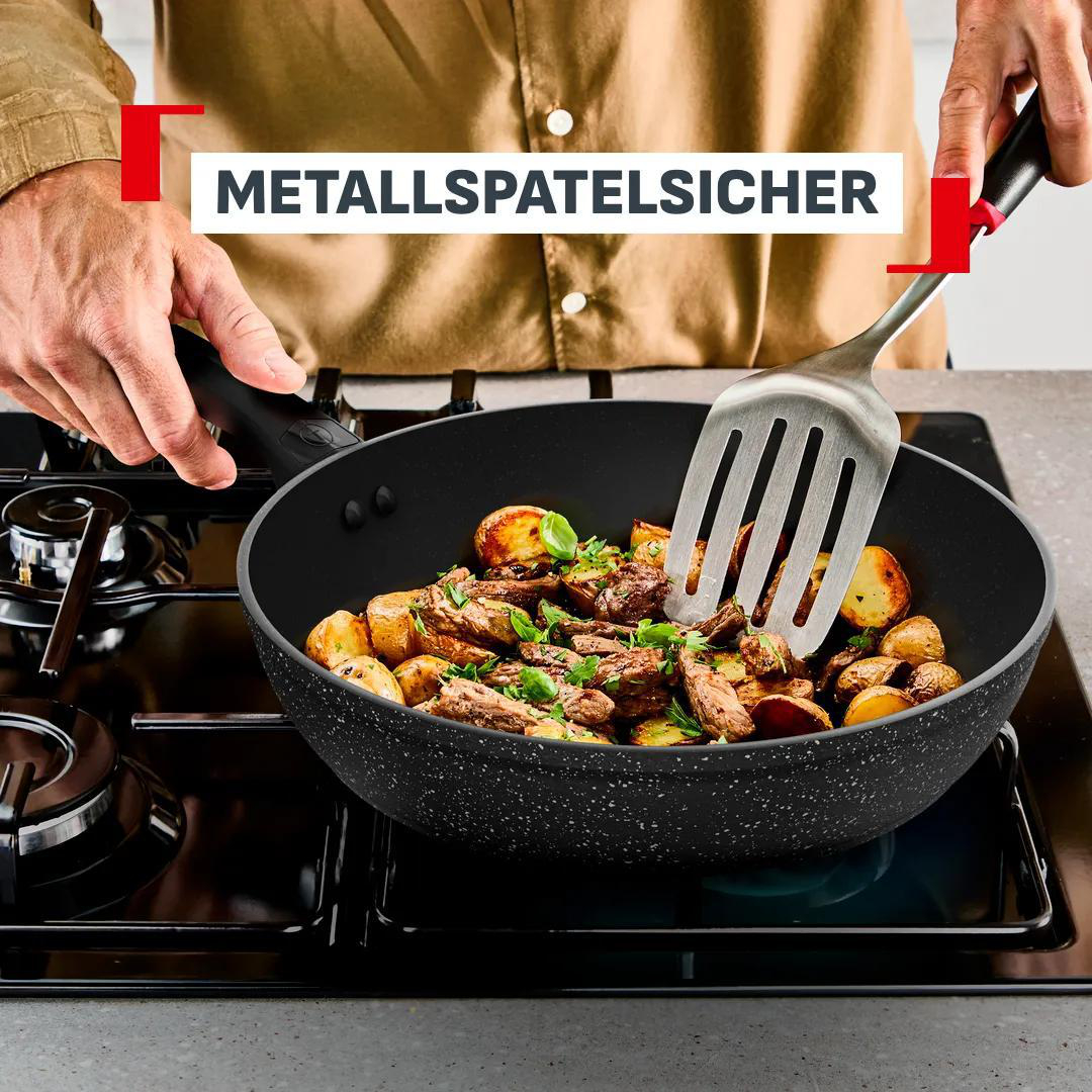 Fleisch und Kartoffeln werden in einer Pfanne mit einem Spatel gebraten.