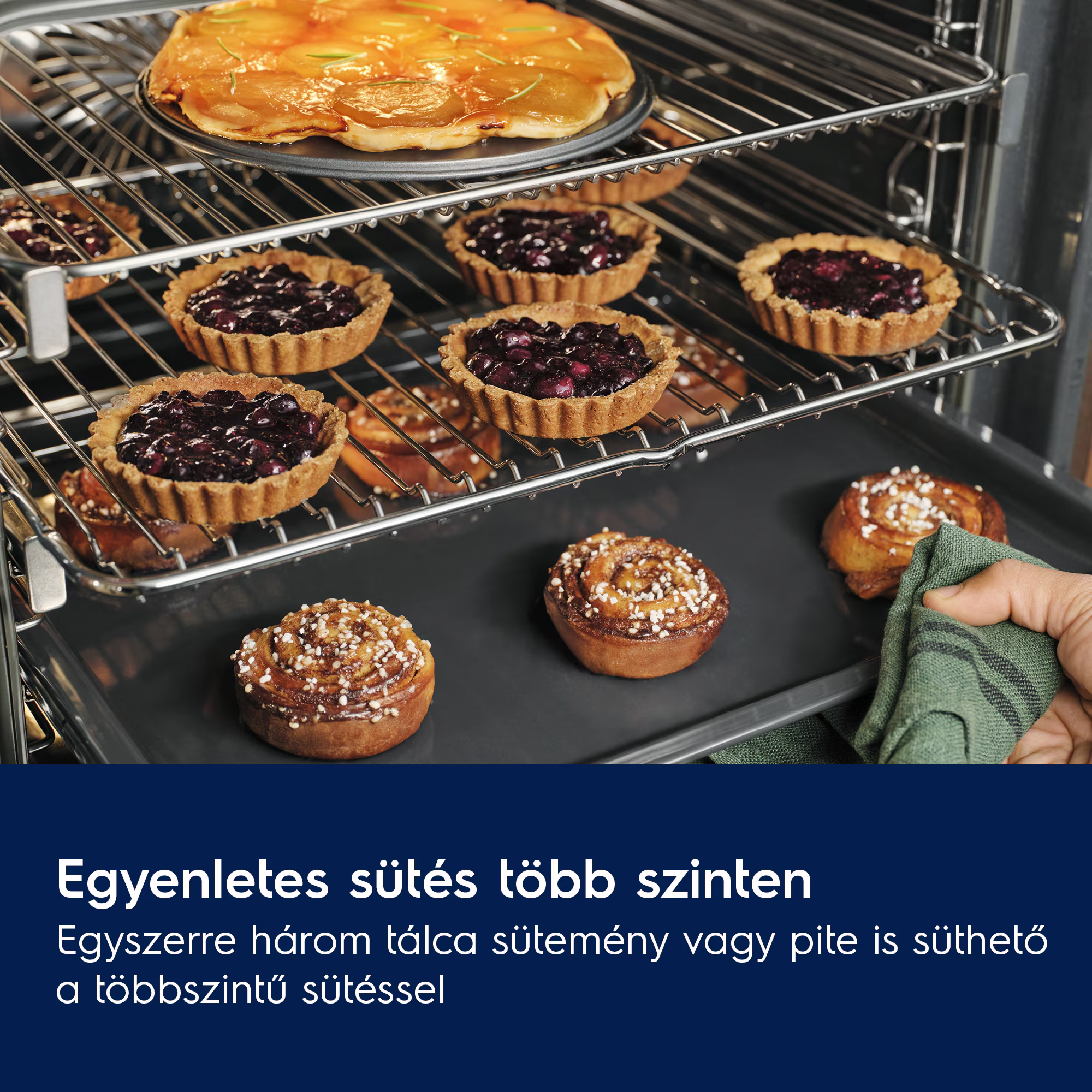 Egy férfi zöld ruhát vesz ki egy sütőből sok süteménnyel.