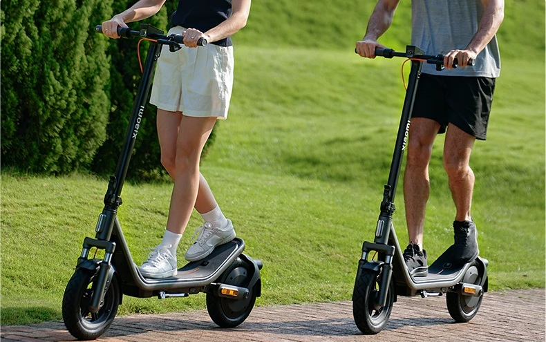 Dwie osoby jadące na hulajnogach elektrycznych po zewnętrznej ścieżce.