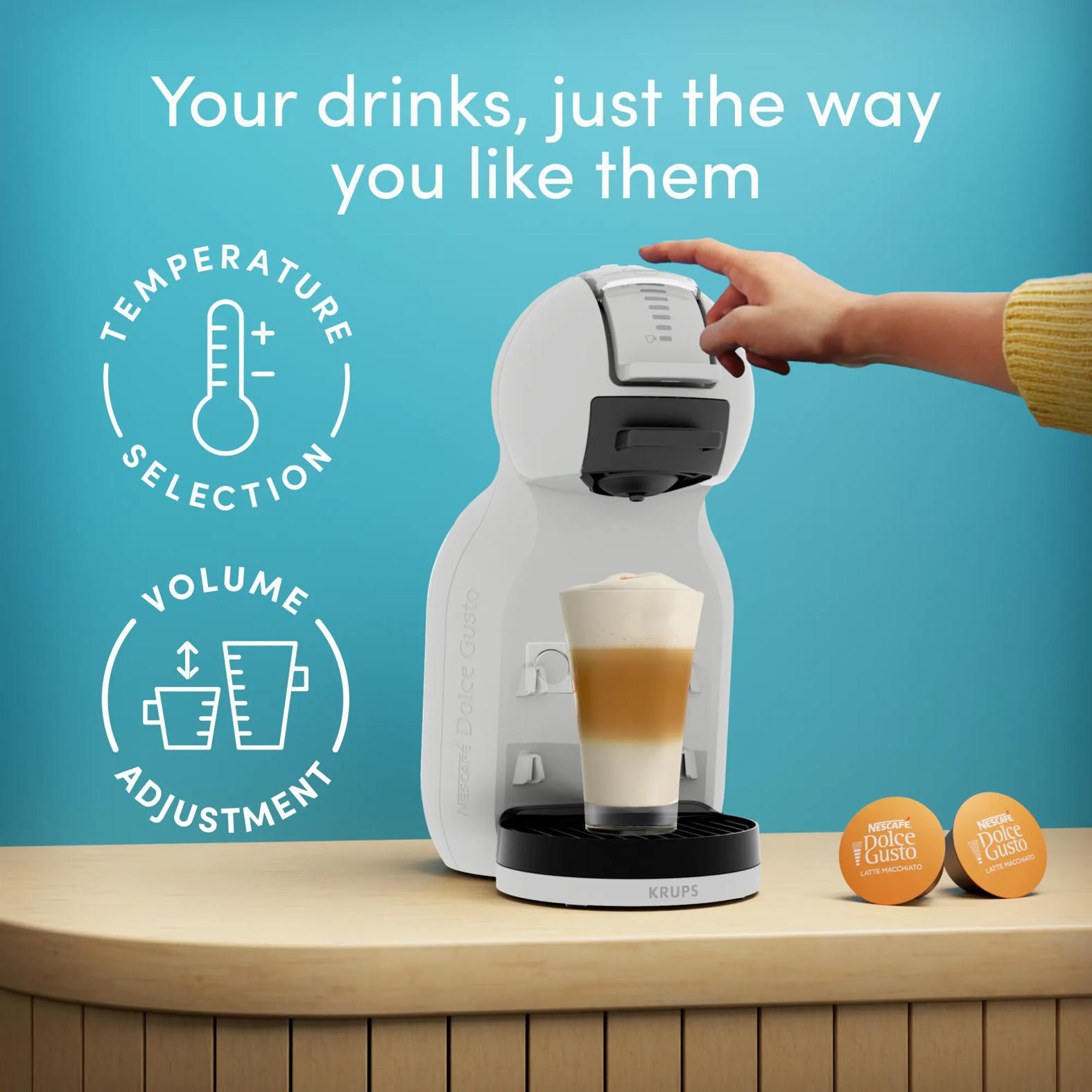 Eine weiße Kaffeemaschine mit einem Glas Latte Macchiato und zwei Kapseln.