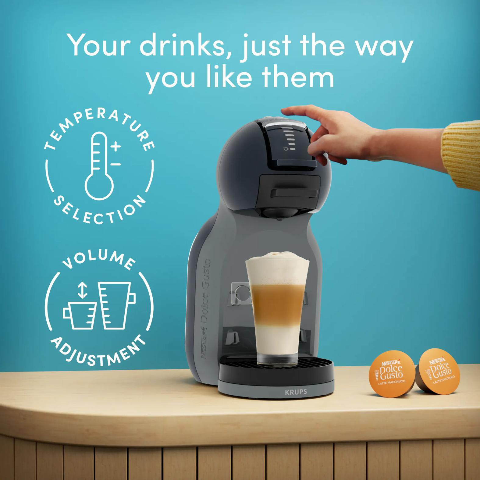 Eine Hand bedient eine Kaffeemaschine mit einem fertigen Latte Macchiato daneben.