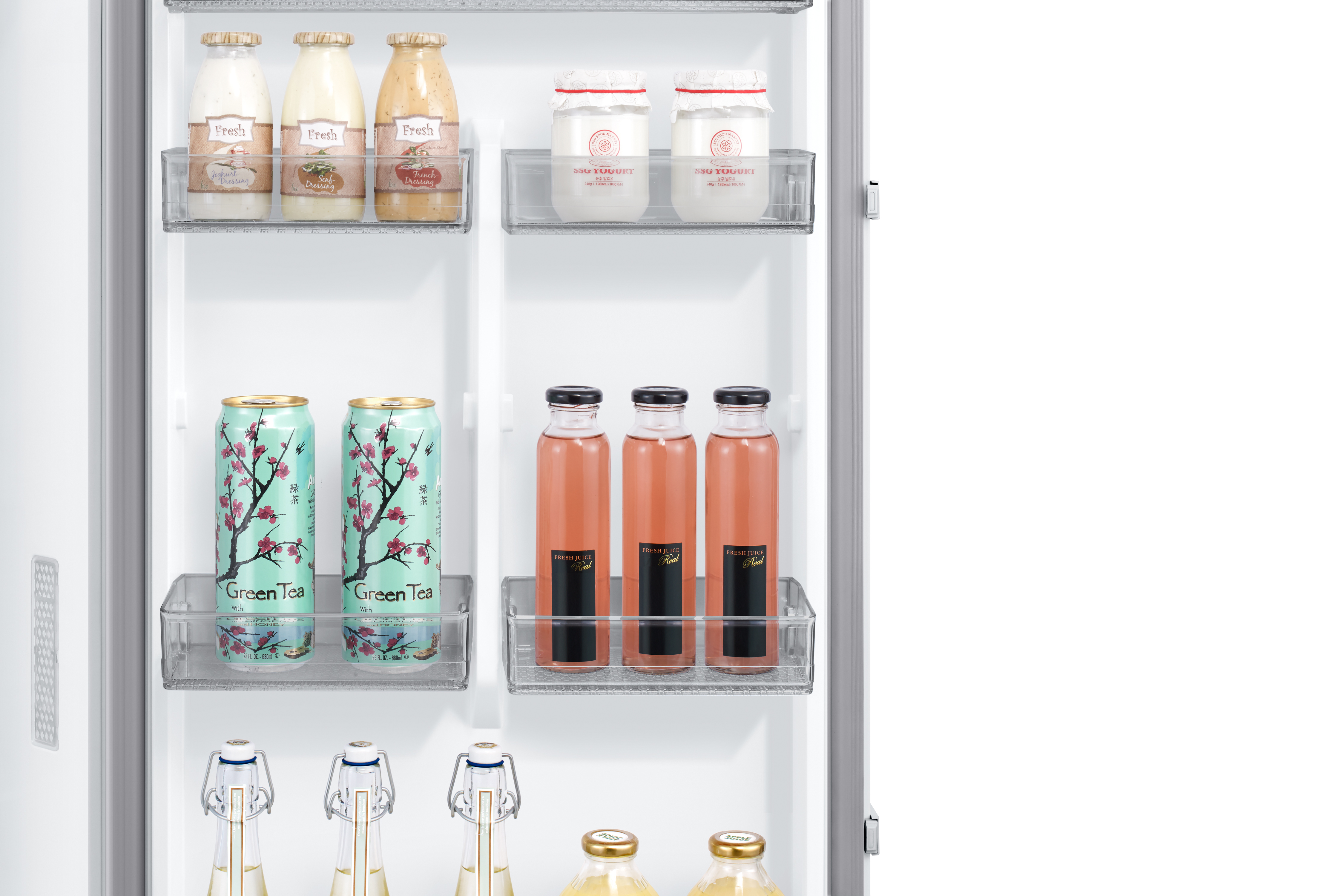 Estantes de refrigerador con yogur, aderezos, latas de té verde y botellas de jugo.
