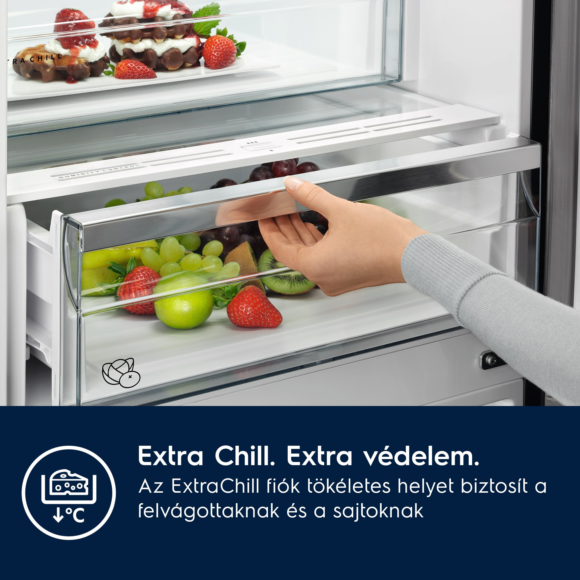 Egy kéz hűtő fiókot nyit gyümölcsökkel; fentről mézeskalács és eper látszik.