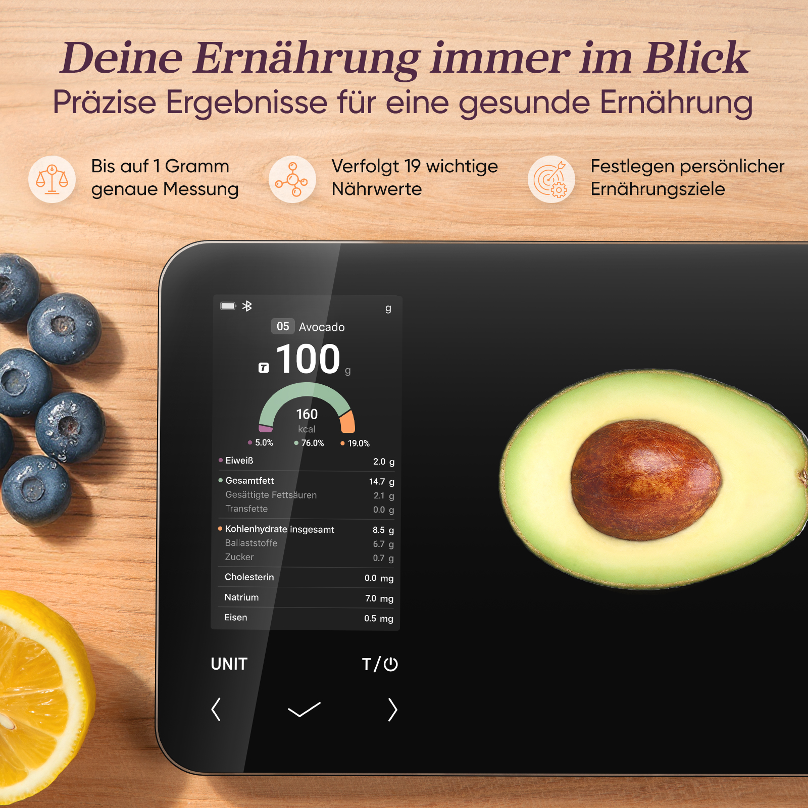Digitalwaage zeigt Nährwerte von Avocado mit 100g an. Blaubeeren und Zitrone daneben.