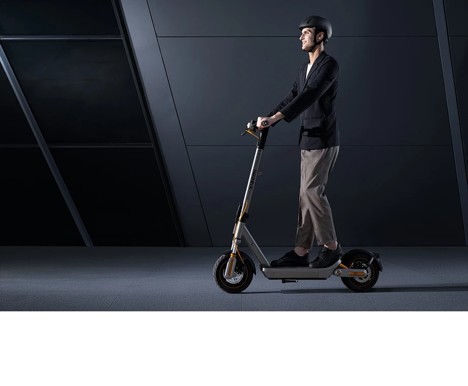 Mężczyzna w garniturze jedzie na hulajnodze elektrycznej z kaskiem.