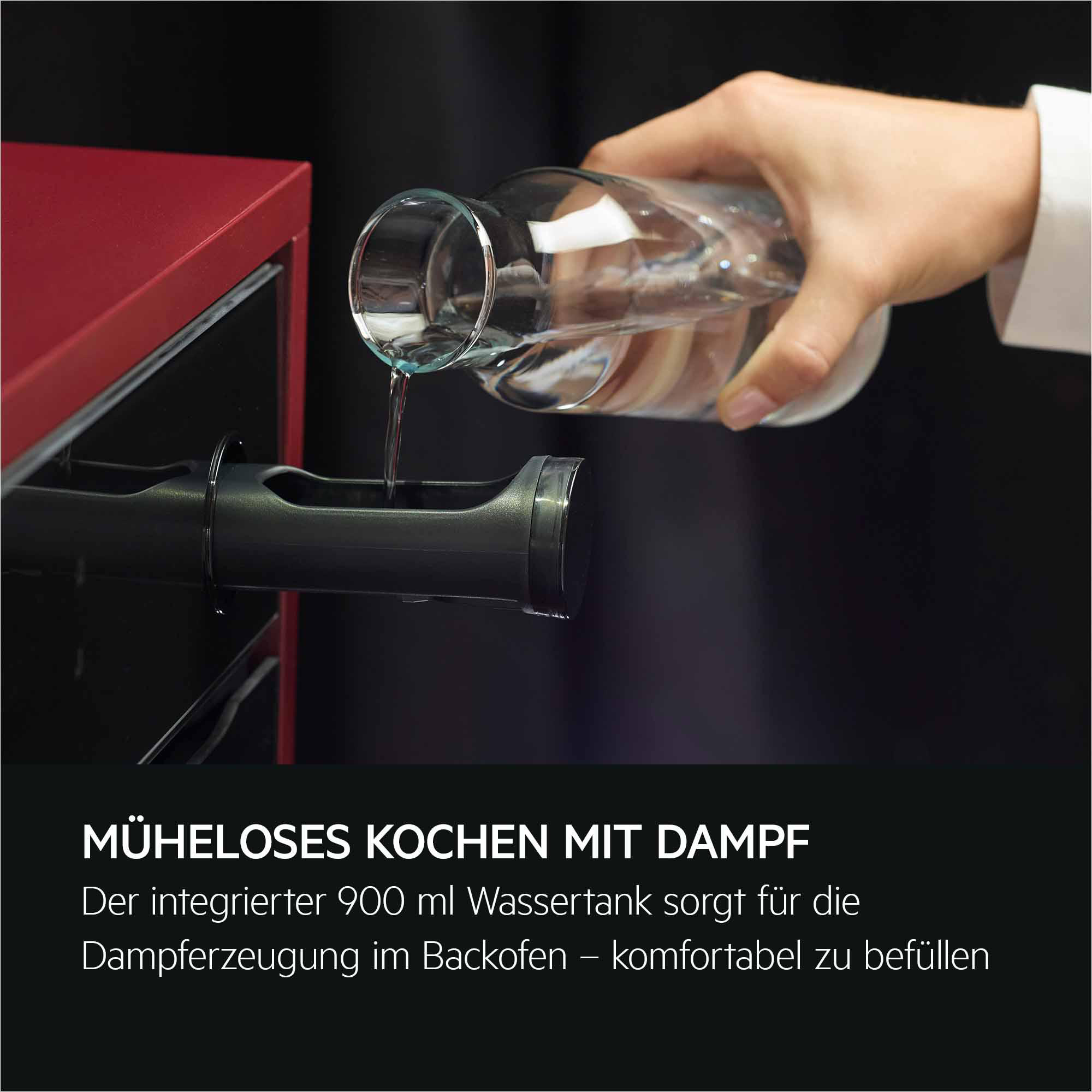 Eine Hand gießt Wasser aus einem Glasbehälter in einen Backofen-Wassertank.
