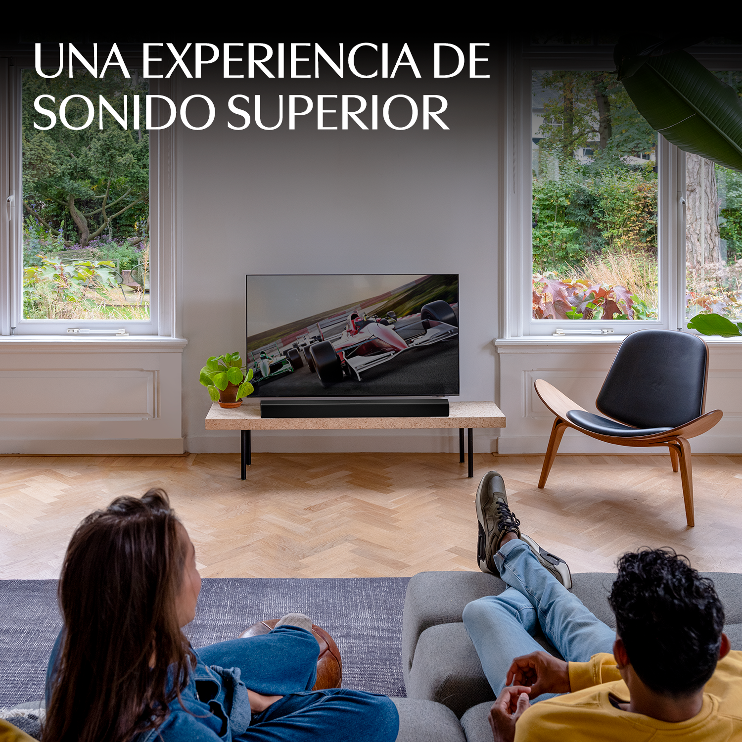 Dos personas se relajan en una sala de estar, viendo un televisor con una carrera de coches.