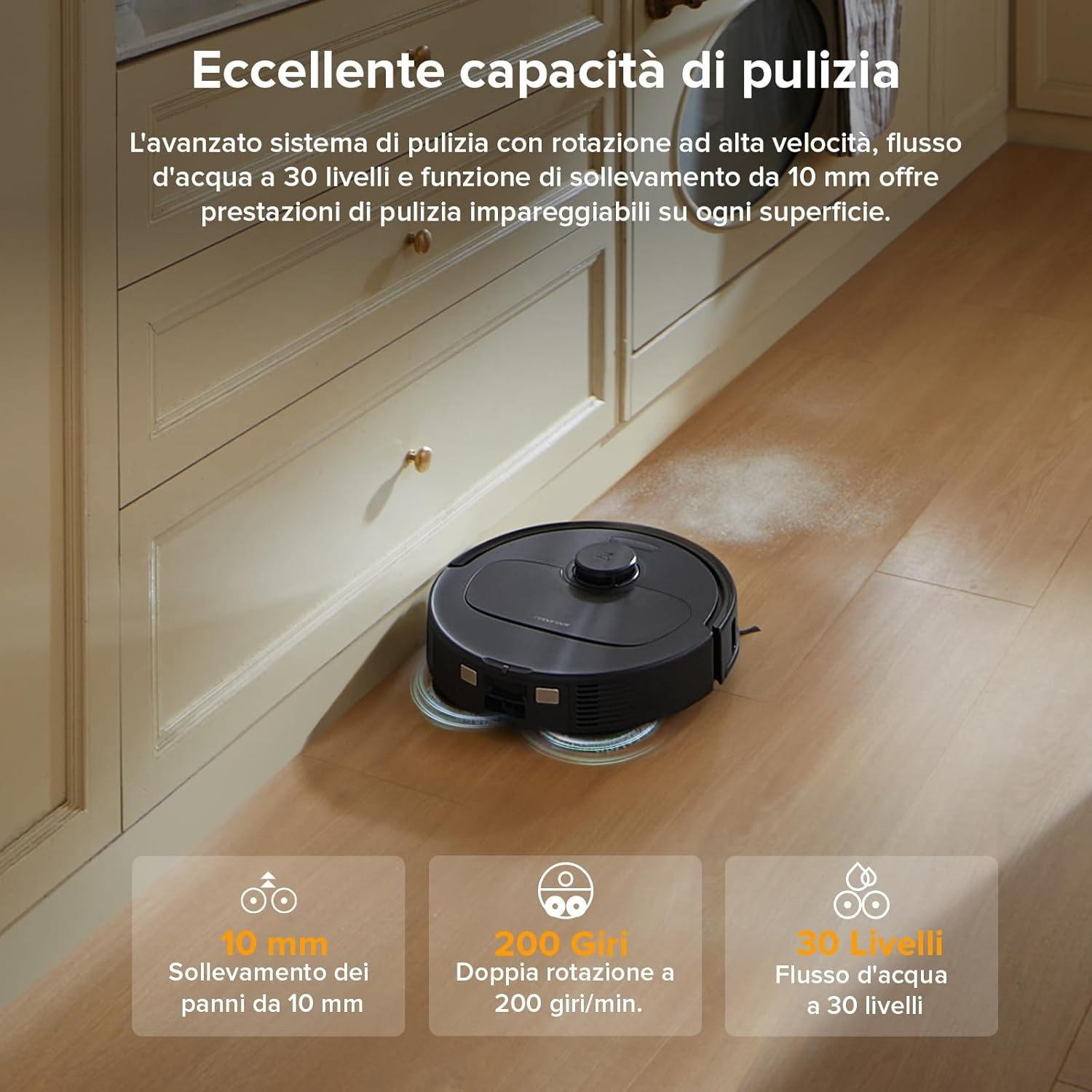 Un robot aspirapolvere nero pulisce un pavimento in legno vicino a mobili bianchi.