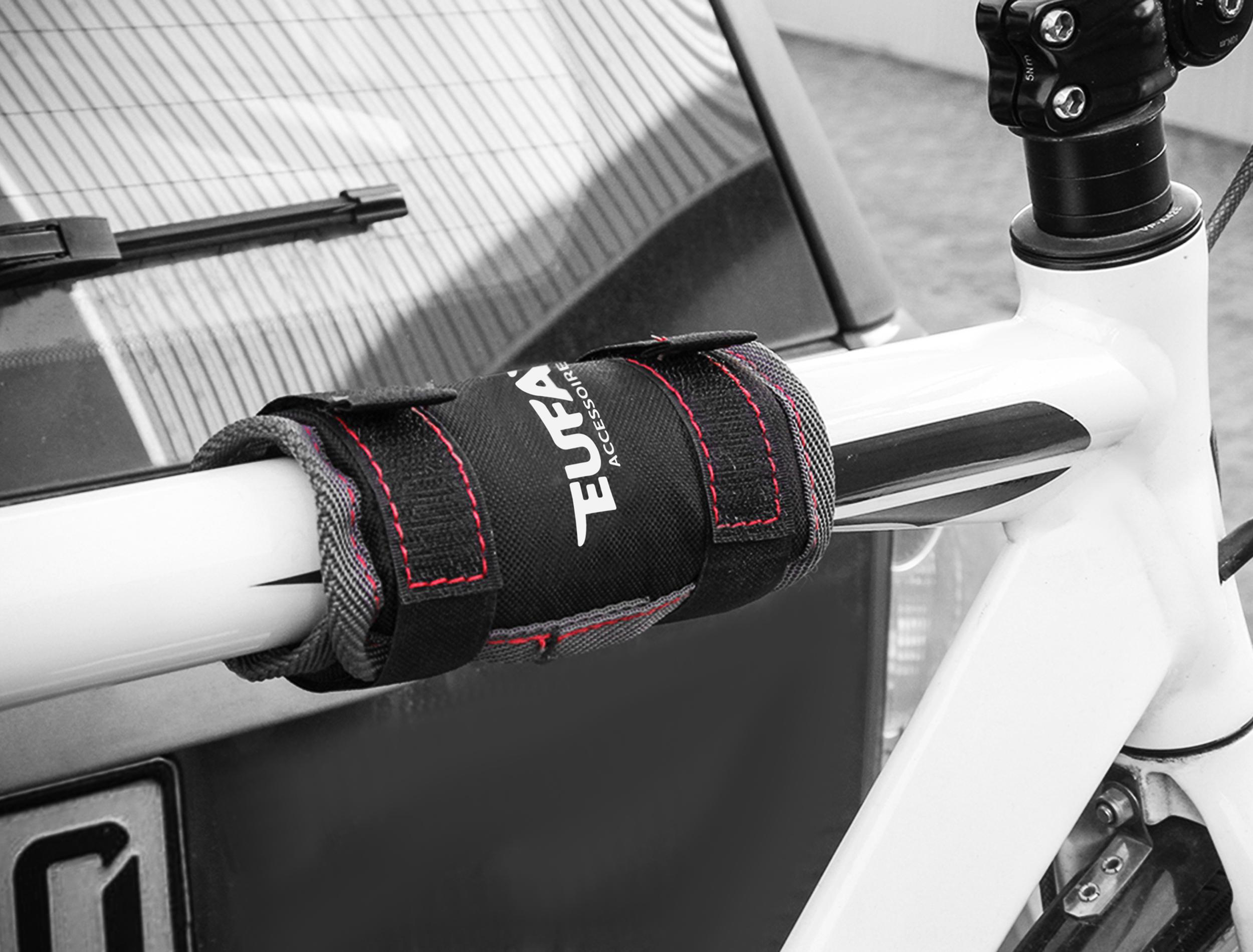 Schwarzes Fahrradschloss mit roter Naht an weißem Fahrradrahmen und Autoheck.