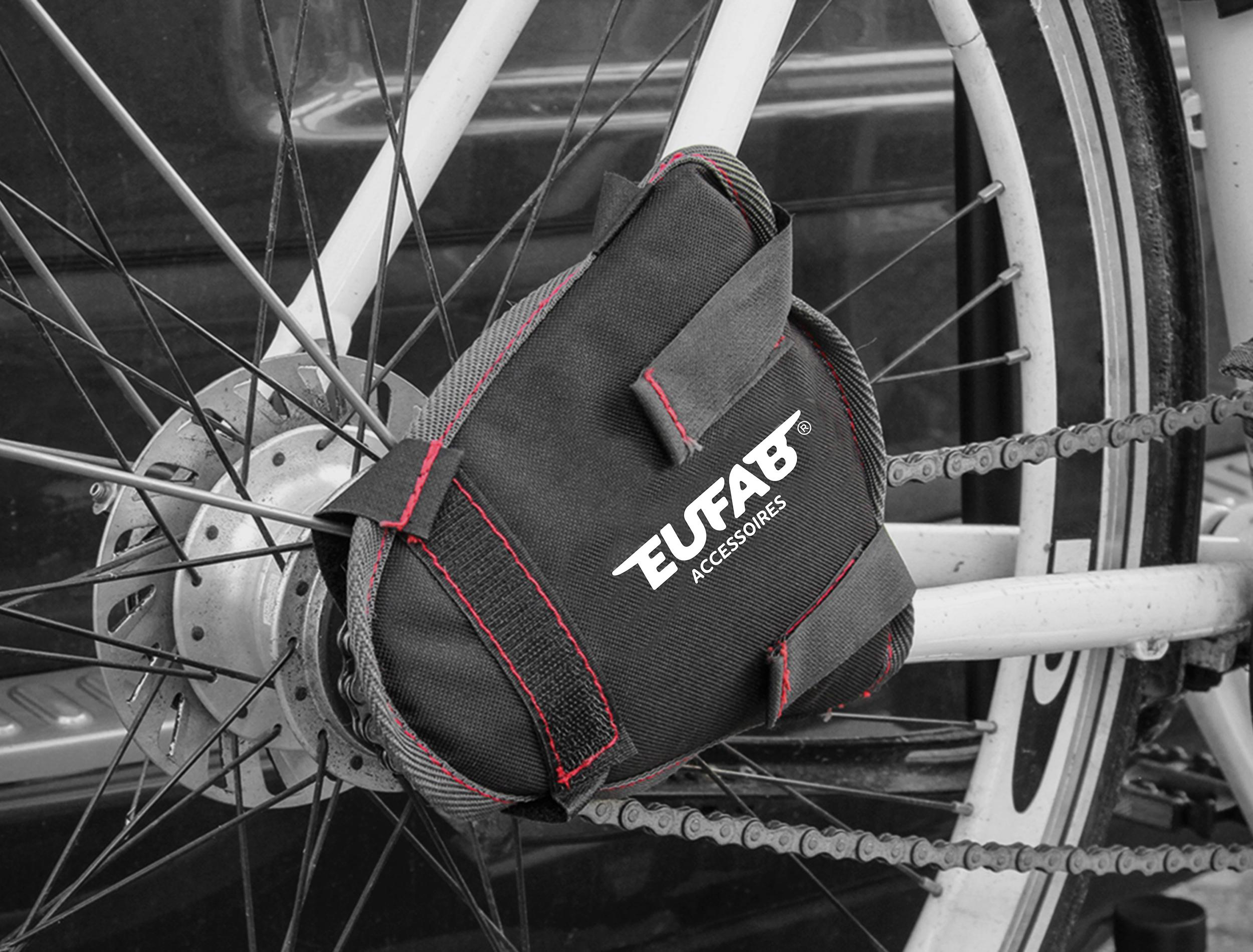 Schwarze Fahrradtasche mit roter Naht, befestigt am Hinterrad, Speichen und Kette.