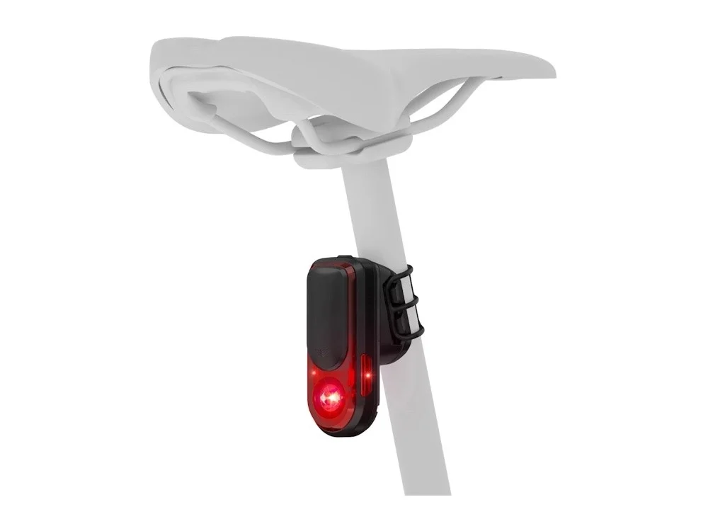 Czerwone tylne światło rowerowe przymocowane do białej sztycy siodła.