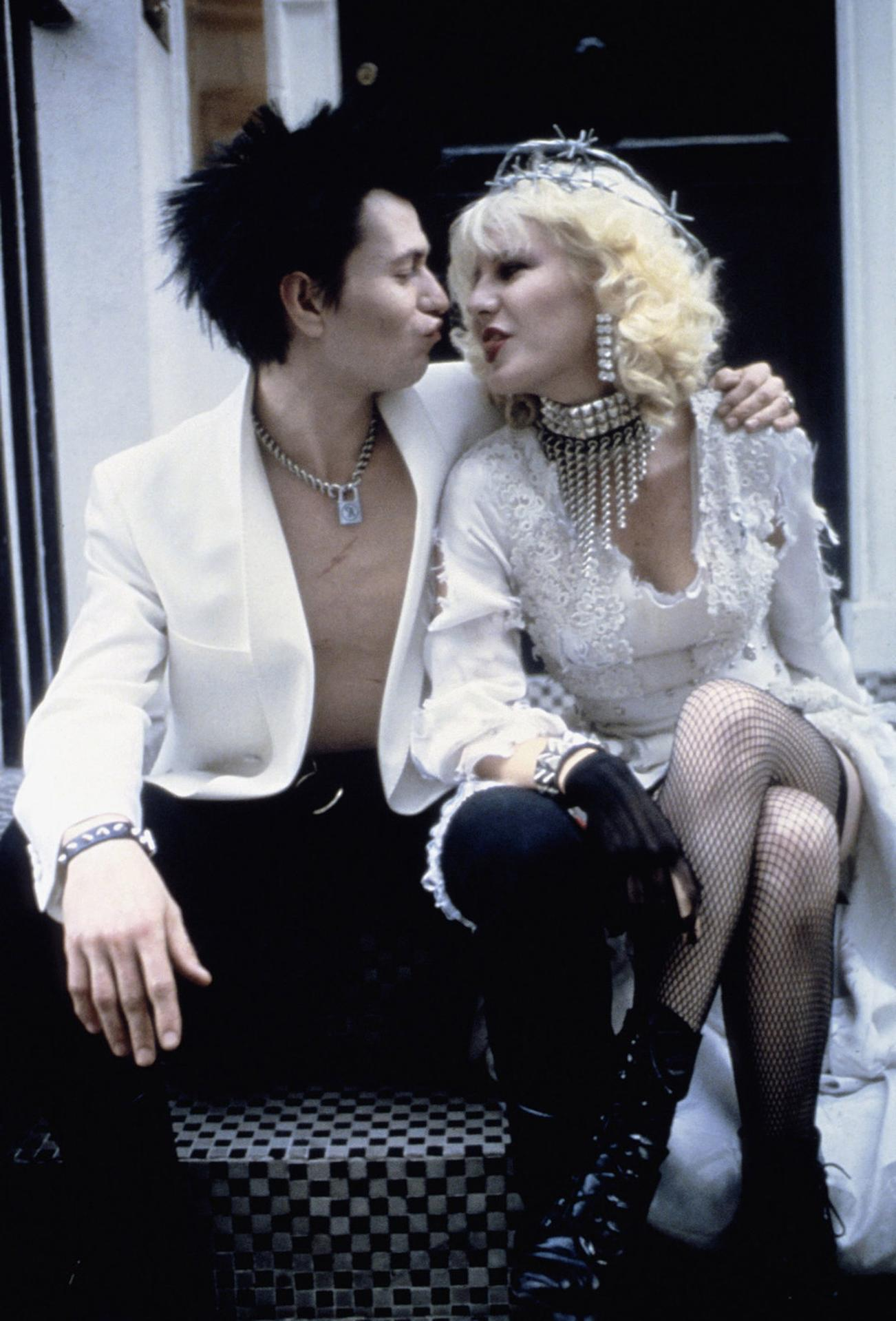 Punk-Paar, Sid Vicious und Nancy Spungen, küssen sich auf Stufen sitzend.