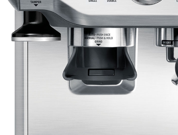 Zbliżenie srebrnej ekspresu do kawy z tamperem i młynkiem.