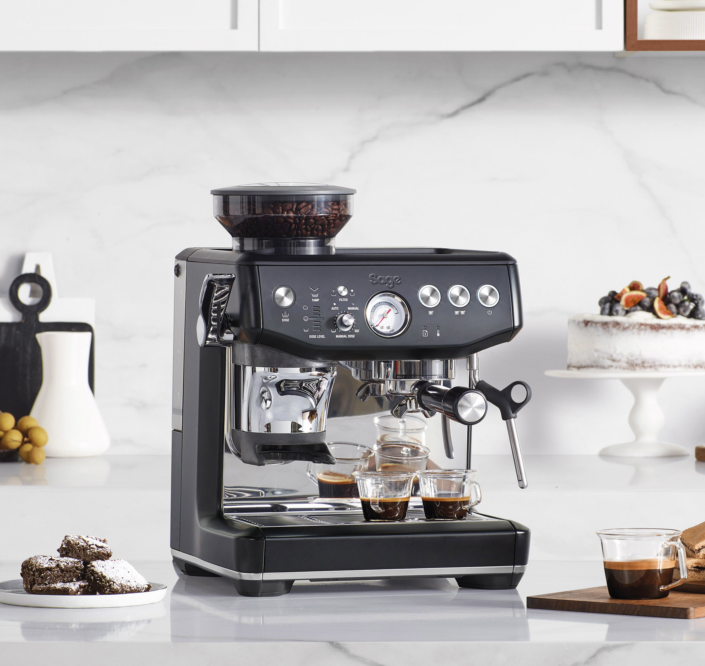 Czarna maszyna do espresso ze zbiornikiem na ziarna, dwoma filiżankami espresso i brownie.