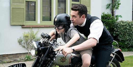 Mann lehrt Kind, Motorrad zu fahren, vor Haus.