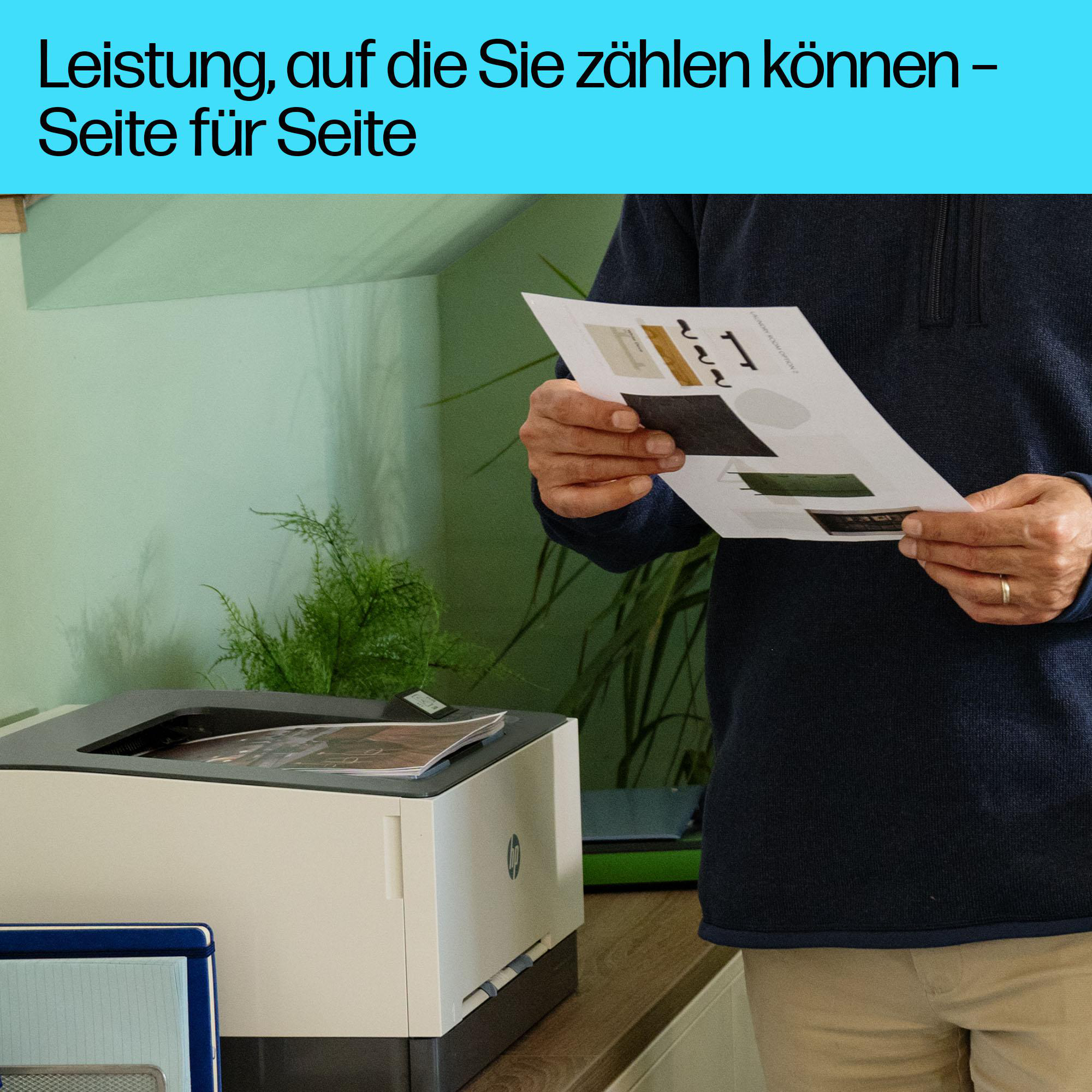 Mann hält Dokumente über Drucker. Grüne Wand im Hintergrund.