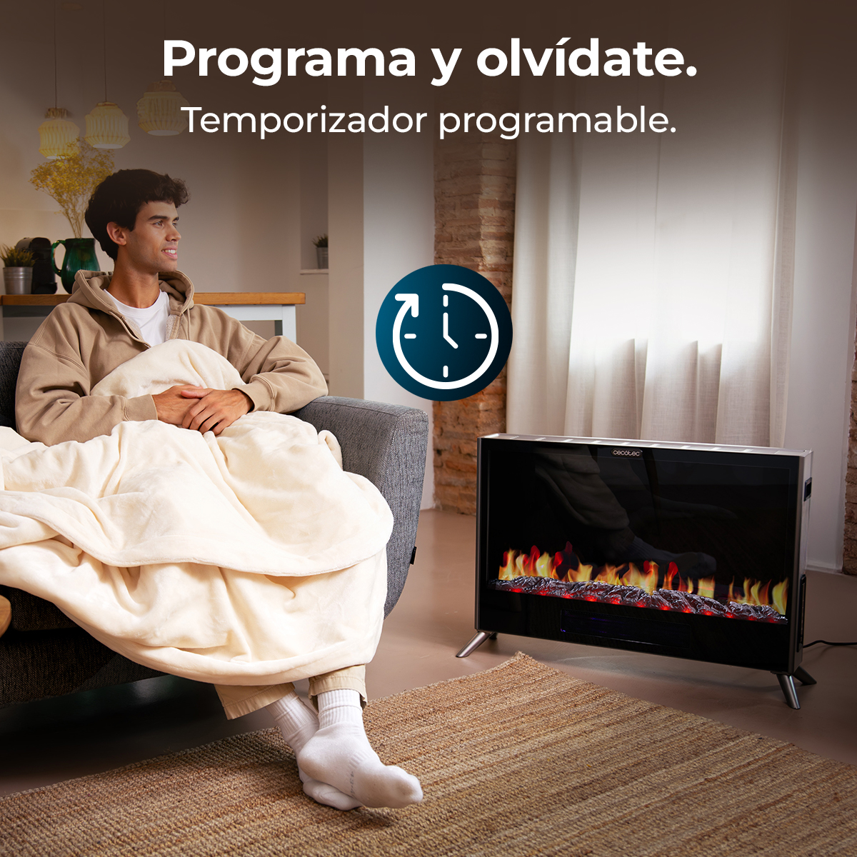 Hombre en sofá envuelto en manta, junto a chimenea eléctrica con llamas.
