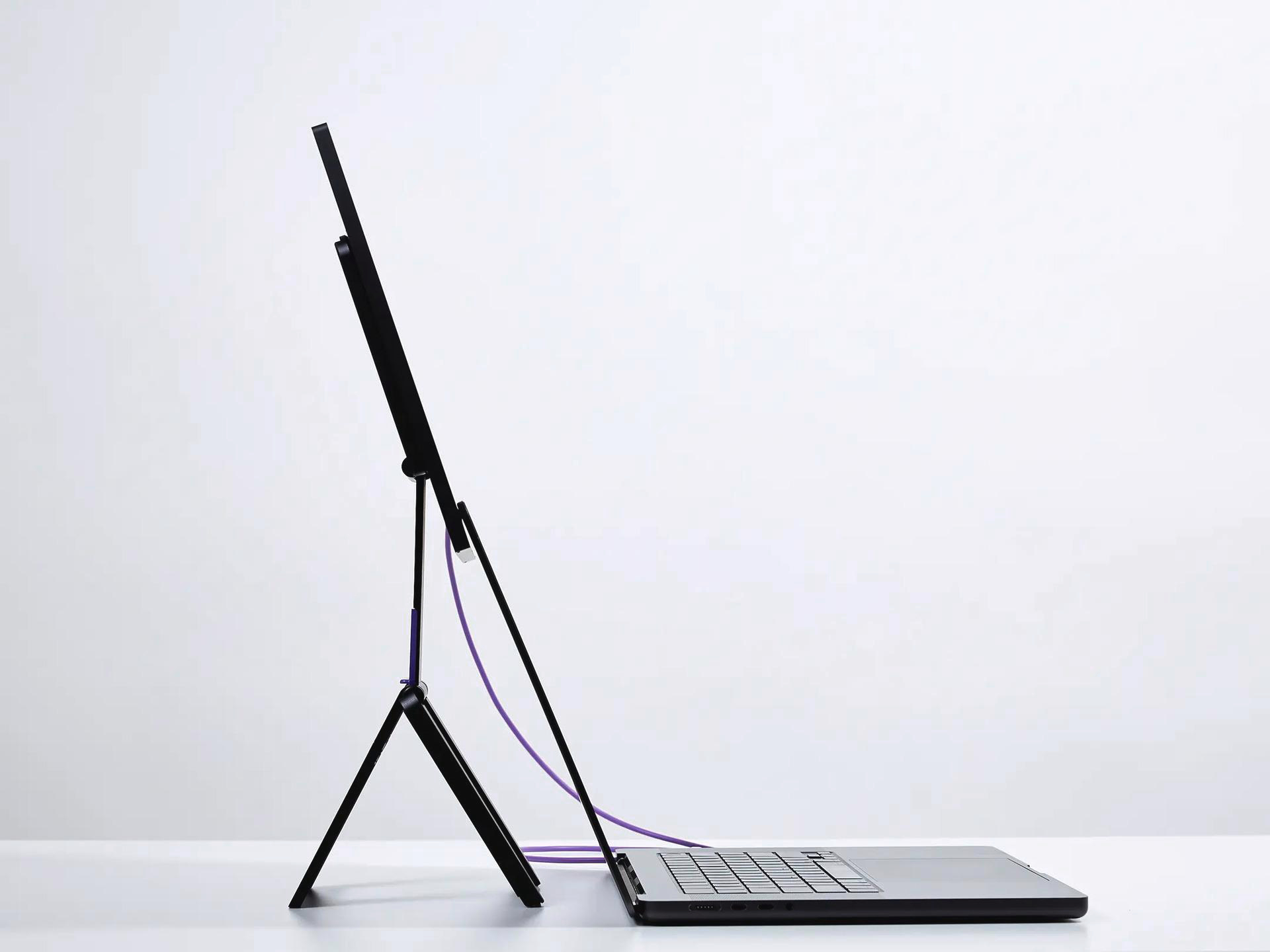 Ein schwarzer Laptop mit einem aufgestellten Bildschirm und einem lila Kabel.