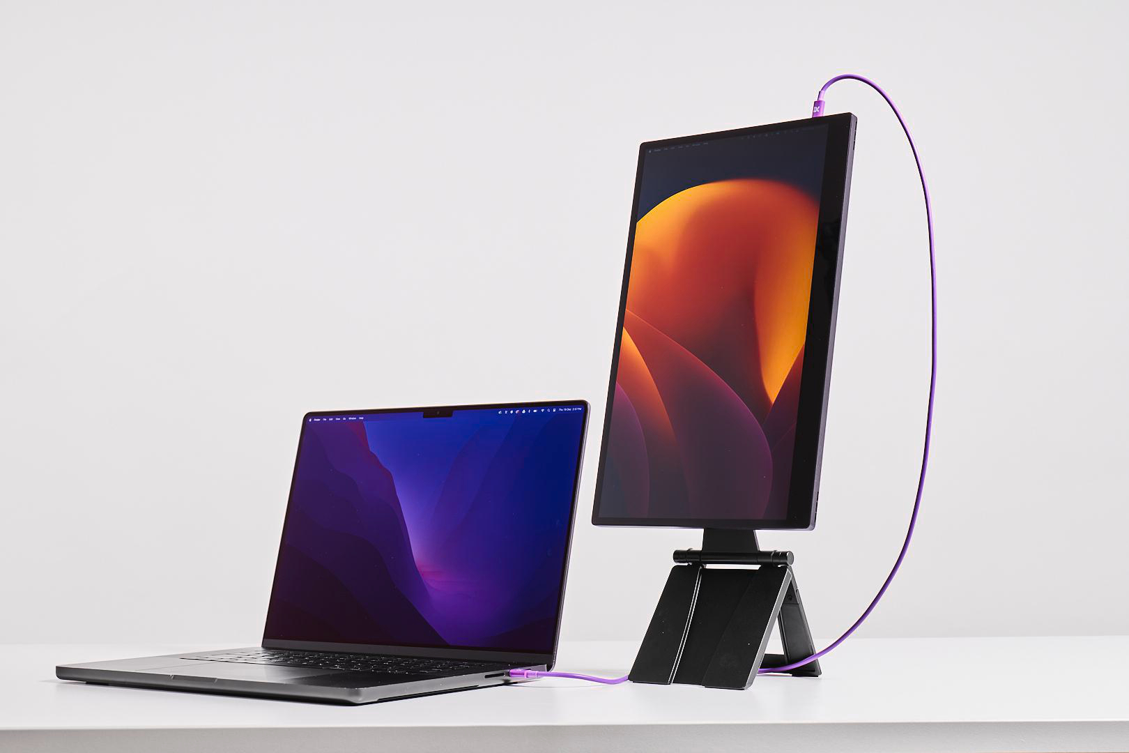 Ein Laptop und ein vertikaler Monitor mit violettem Kabel verbunden.