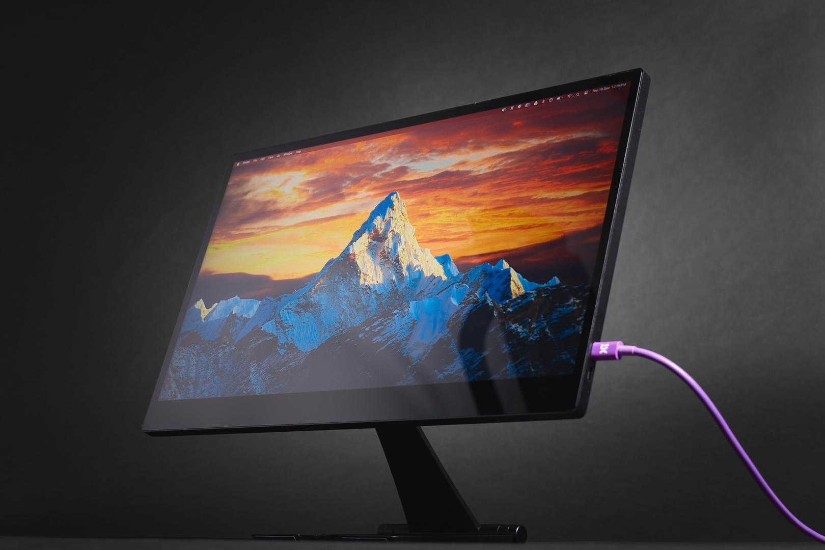 Ein Monitor mit Berg-Hintergrund und lila Kabel, das eingesteckt ist.