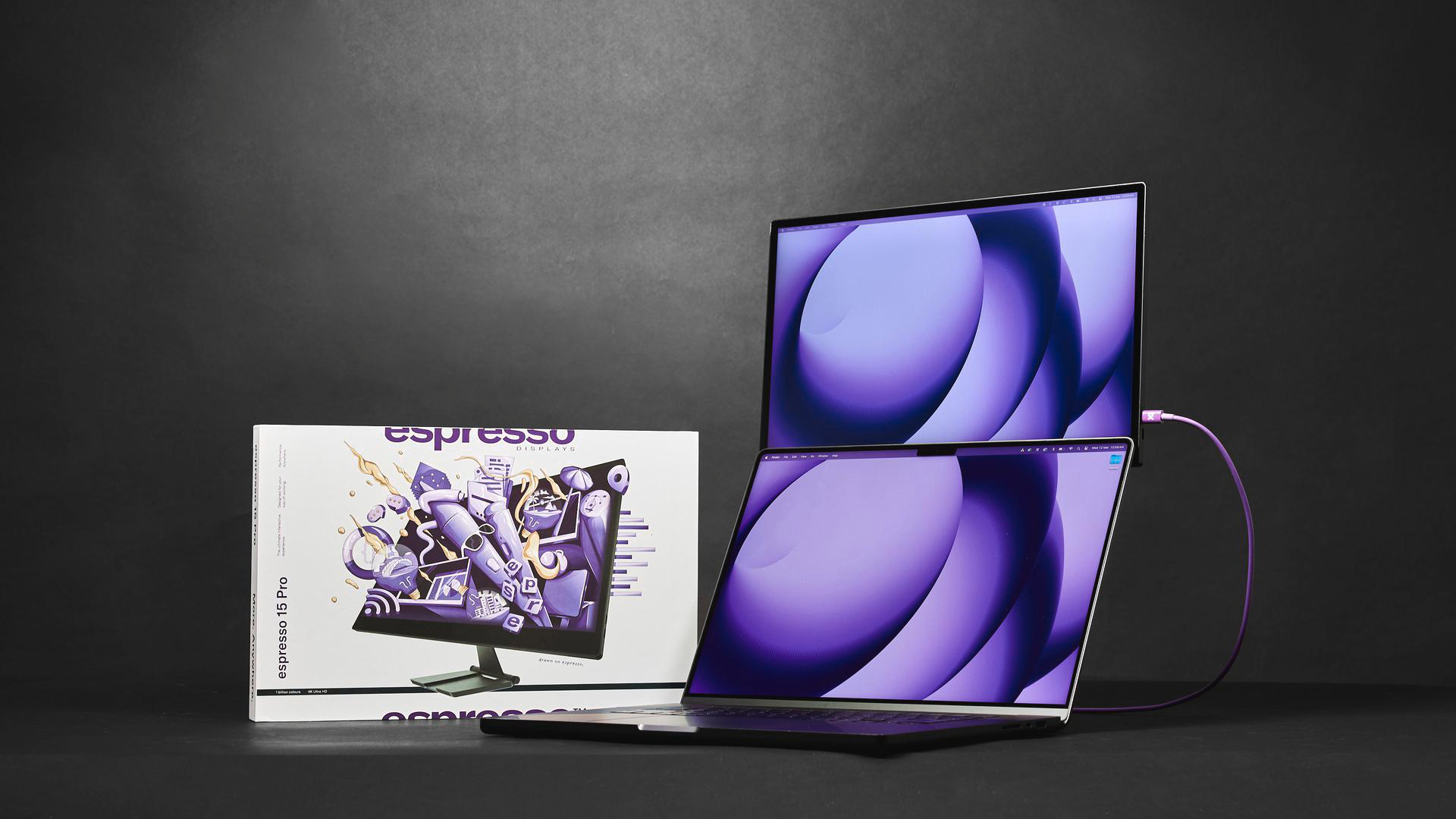 Ein Laptop ist über ein lila Kabel mit einem externen Monitor verbunden.