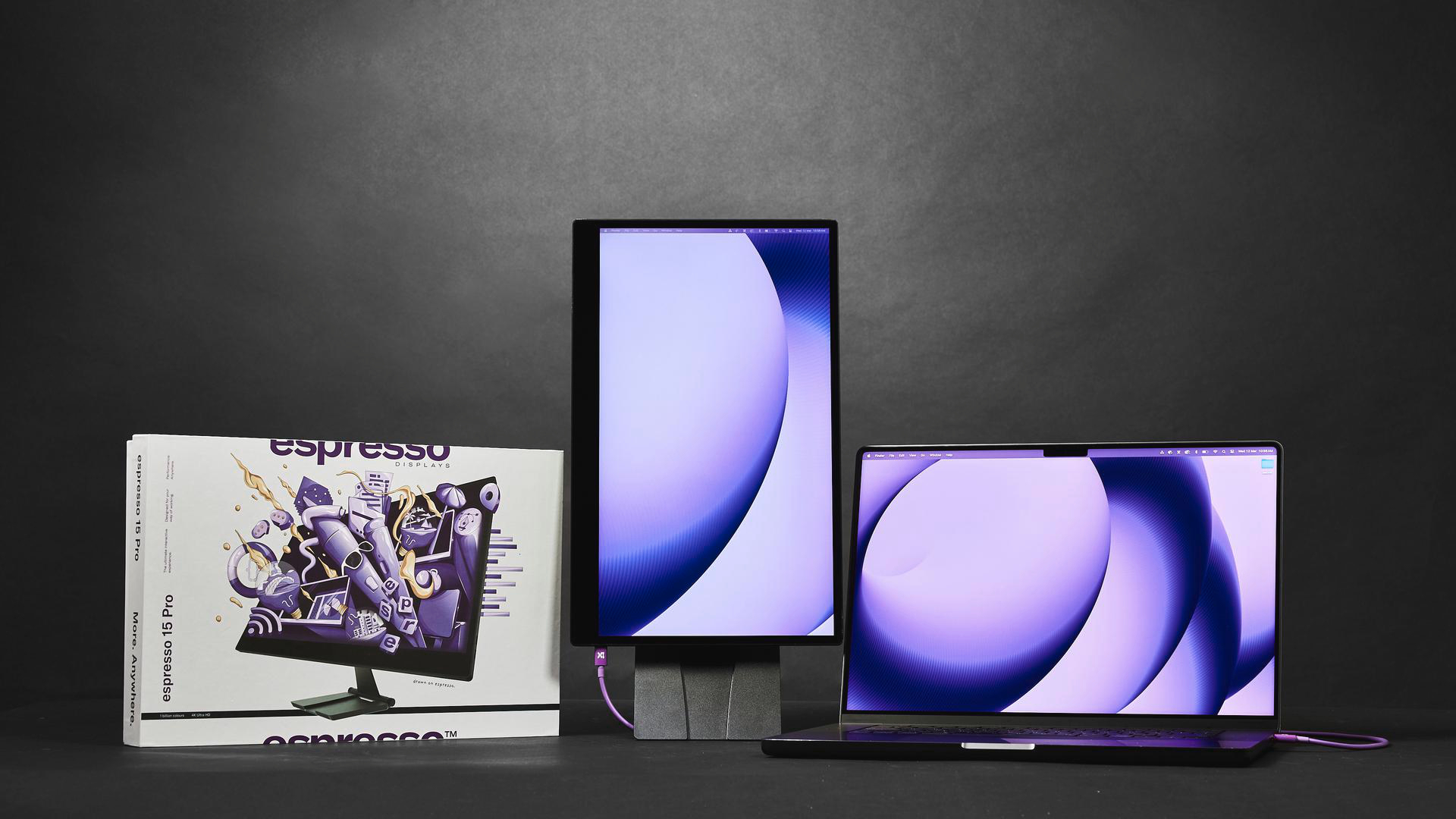Ein vertikaler Monitor und ein Laptop mit lila Hintergrundbild.