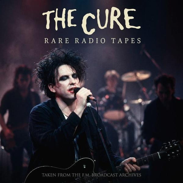 Robert Smith von The Cure singt und spielt Gitarre, Band im Hintergrund.