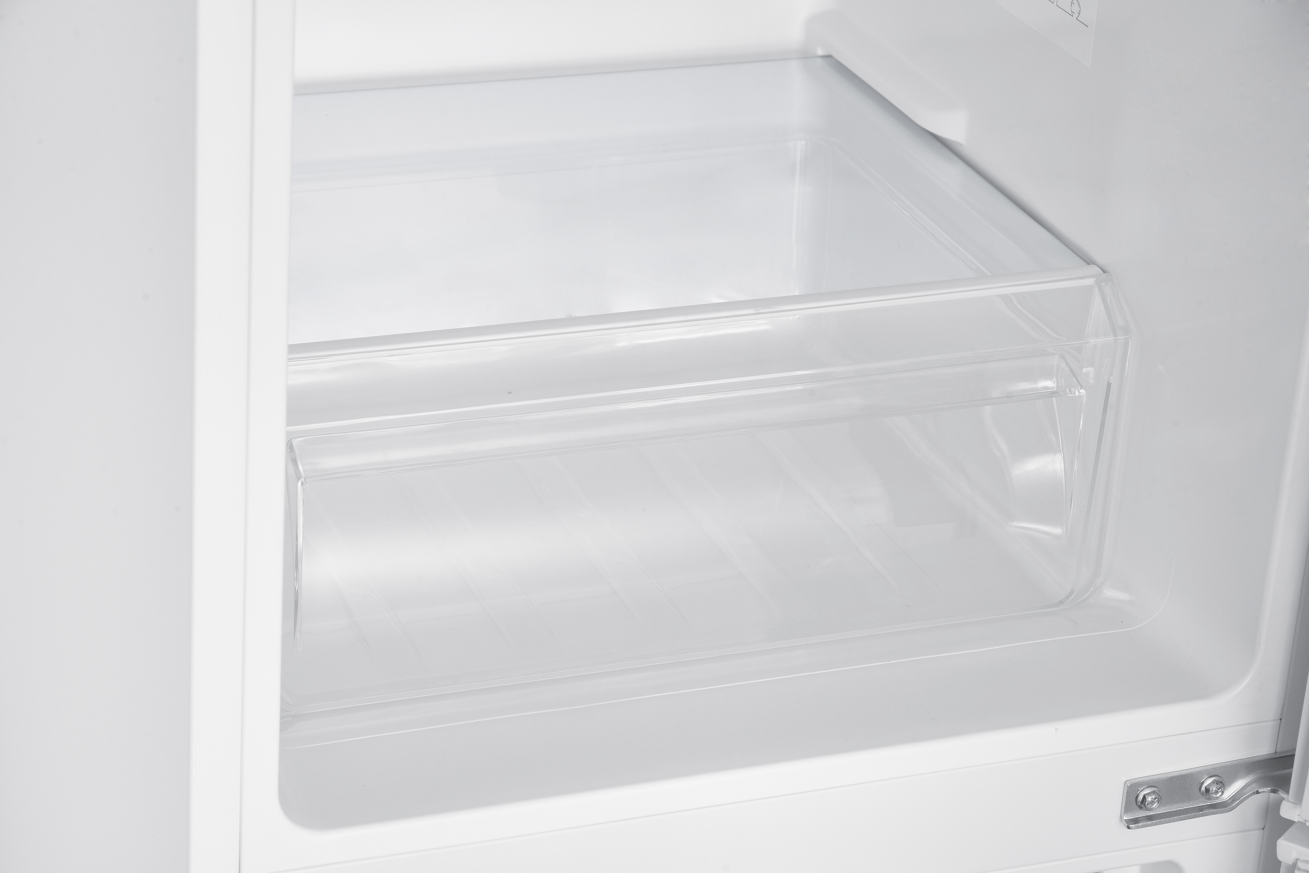Ein leerer, weißer Kühlschrank mit durchsichtiger Schublade und Metallscharnier.