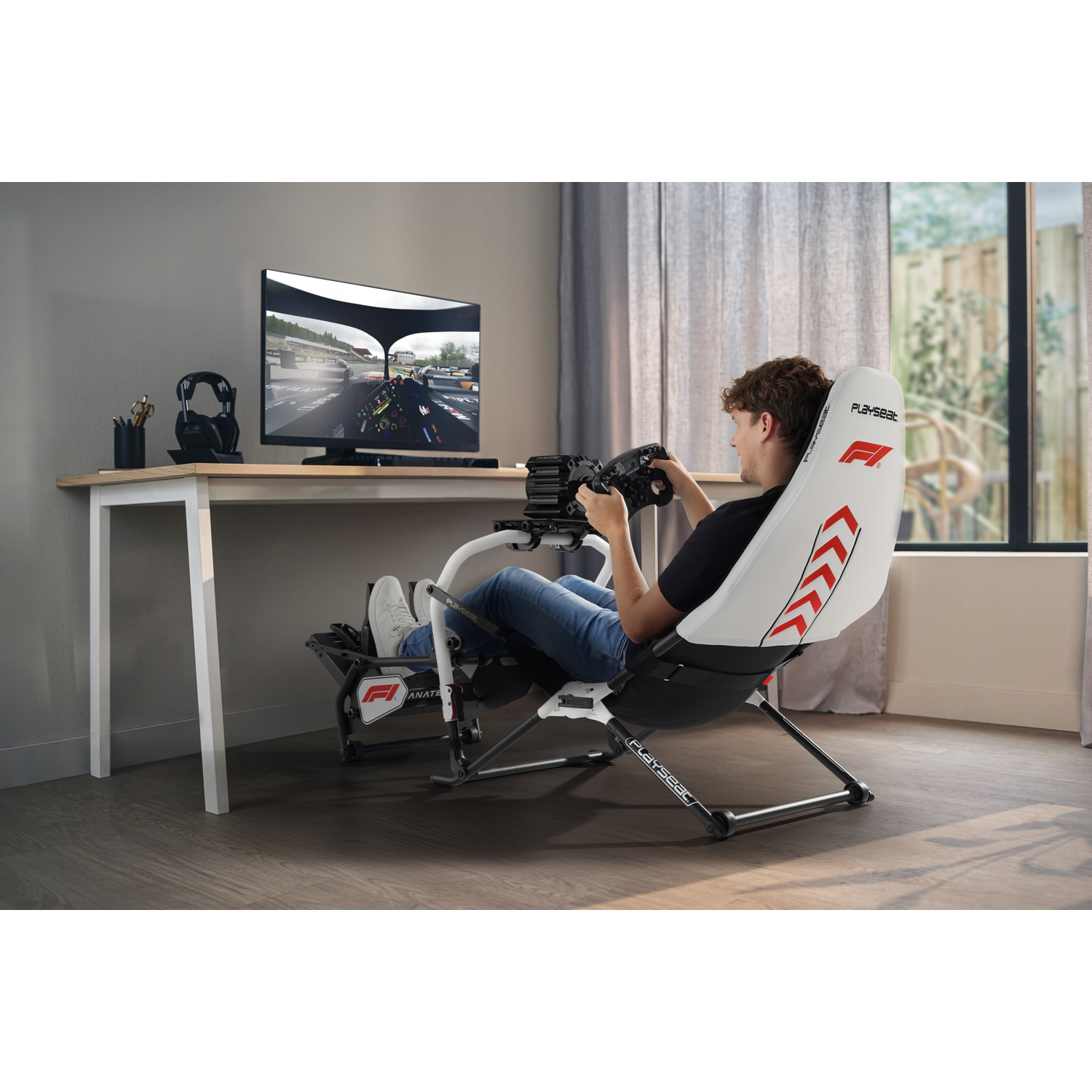 Man in racegame stoel met stuur, spelend op scherm.
