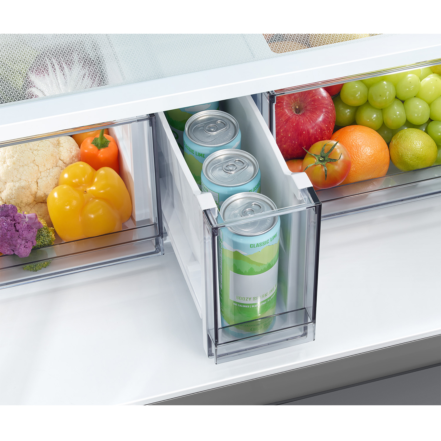 Un cajón de refrigerador con frutas, verduras y latas.