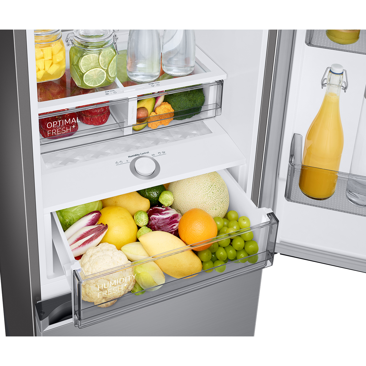 Refrigerador abierto con cajones llenos de frutas y verduras. Una botella de zumo de naranja.