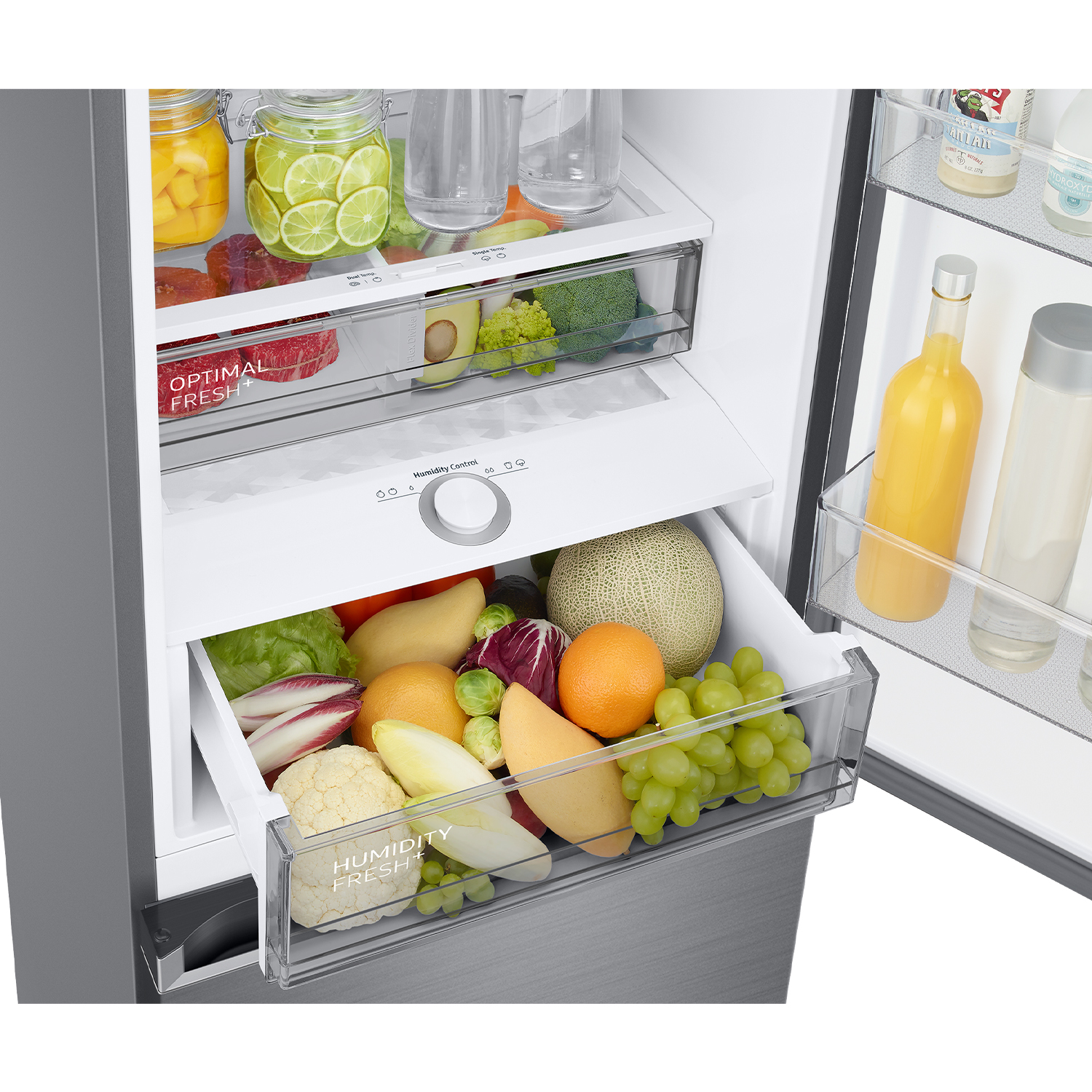 Cajón abierto de refrigerador con productos frescos: frutas, verduras y bebidas.